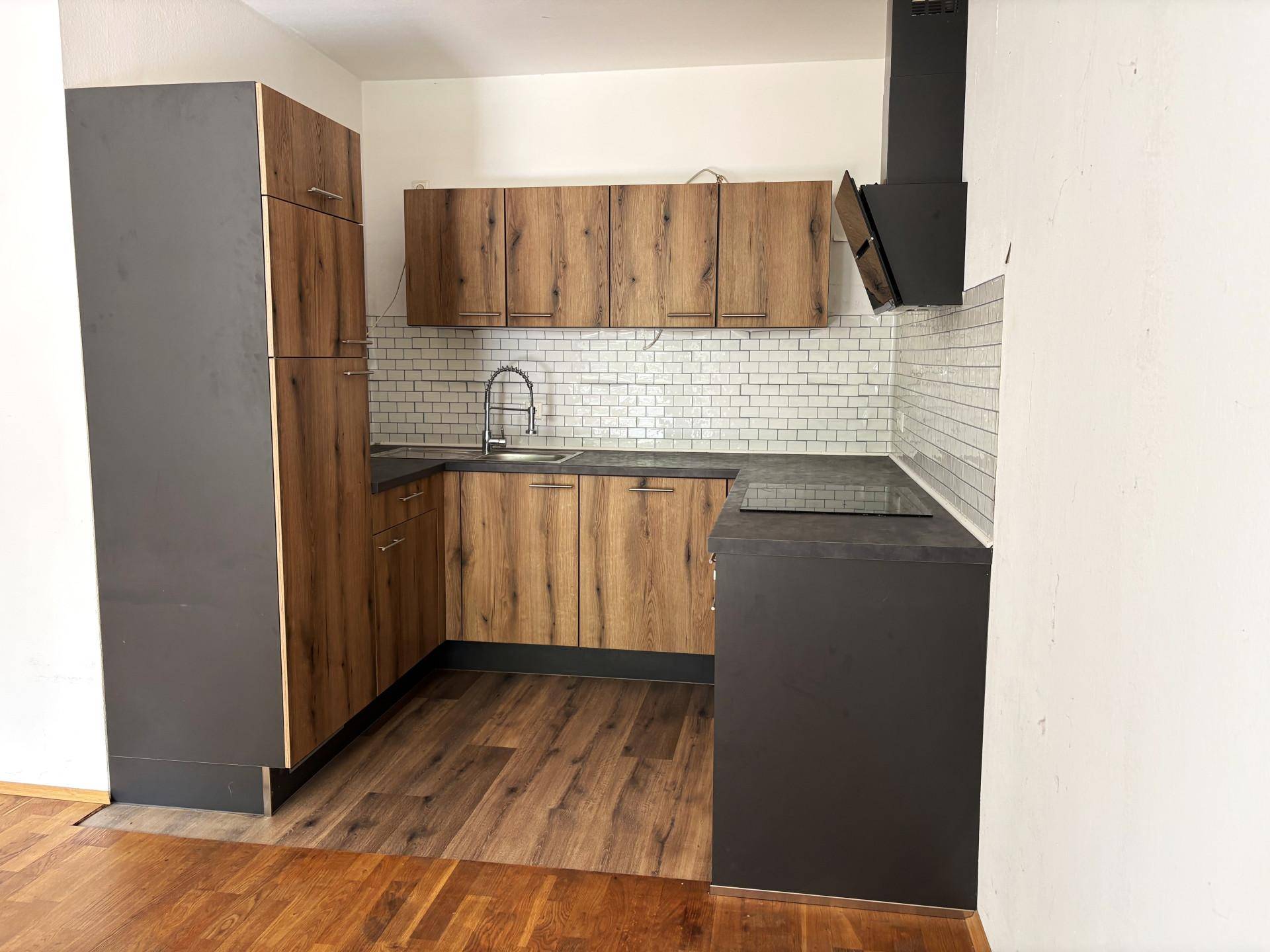 Moderne Küche mit Holzfronten, dunklen Arbeitsplatten und weißem Fliesenspiegel.