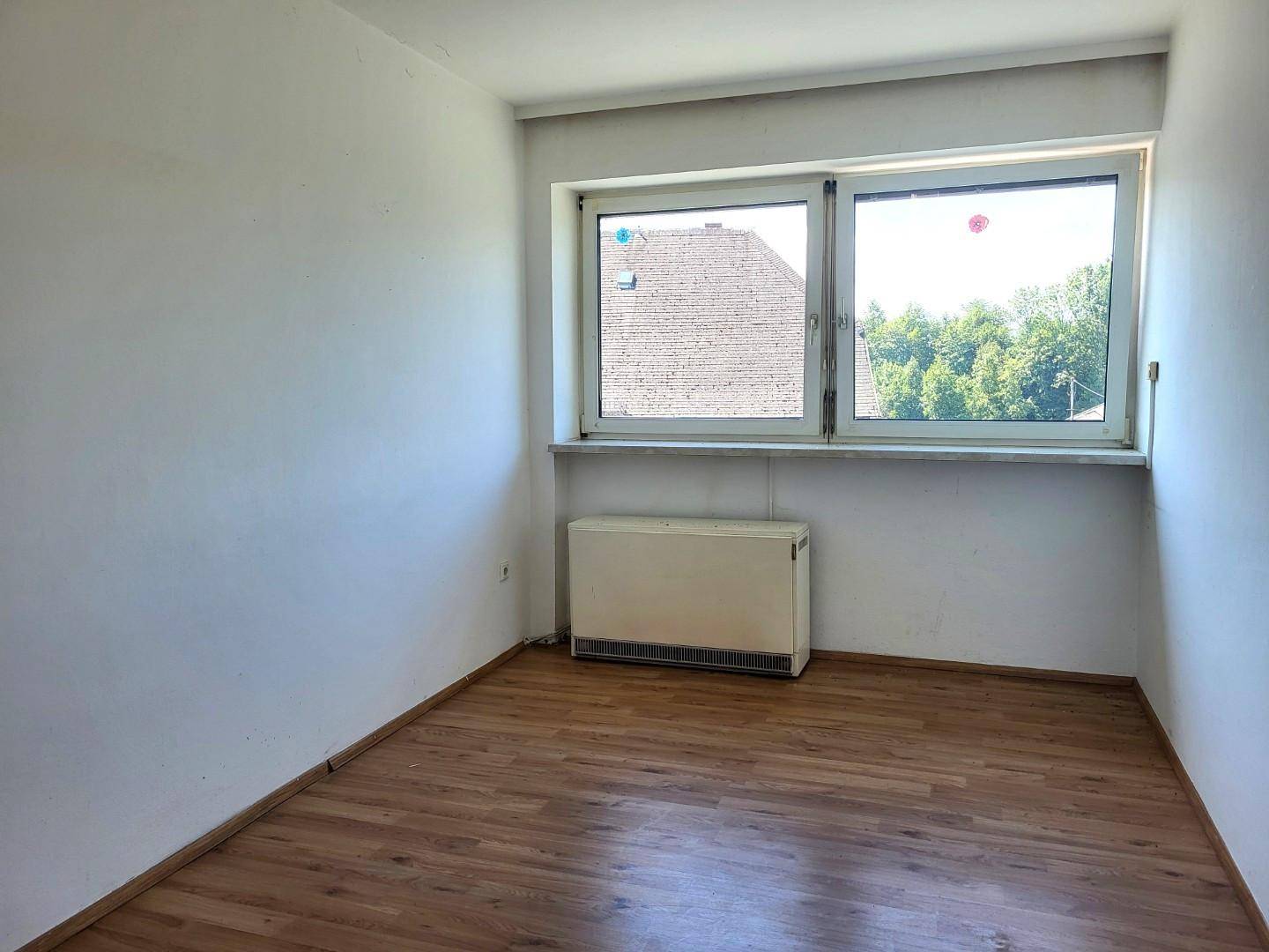 Kleiner, heller Raum mit Laminatboden und Fenster, ideal als Schlaf- oder Arbeitszimmer.
