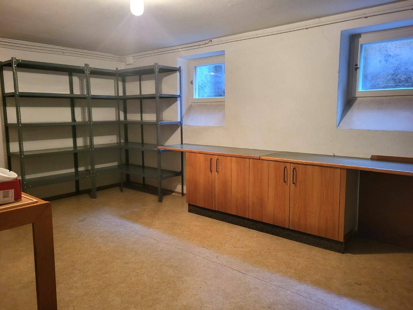 Praktischer Kellerraum mit Regalen und Arbeitsfläche, ausgestattet für Lagerzwecke.