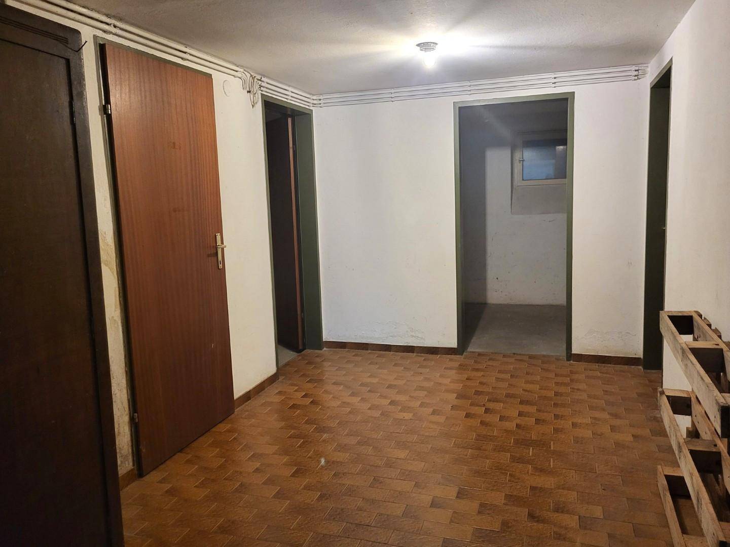 Kellerraum mit Holzparkettboden und einfacher Beleuchtung, ideal als Lagerfläche.