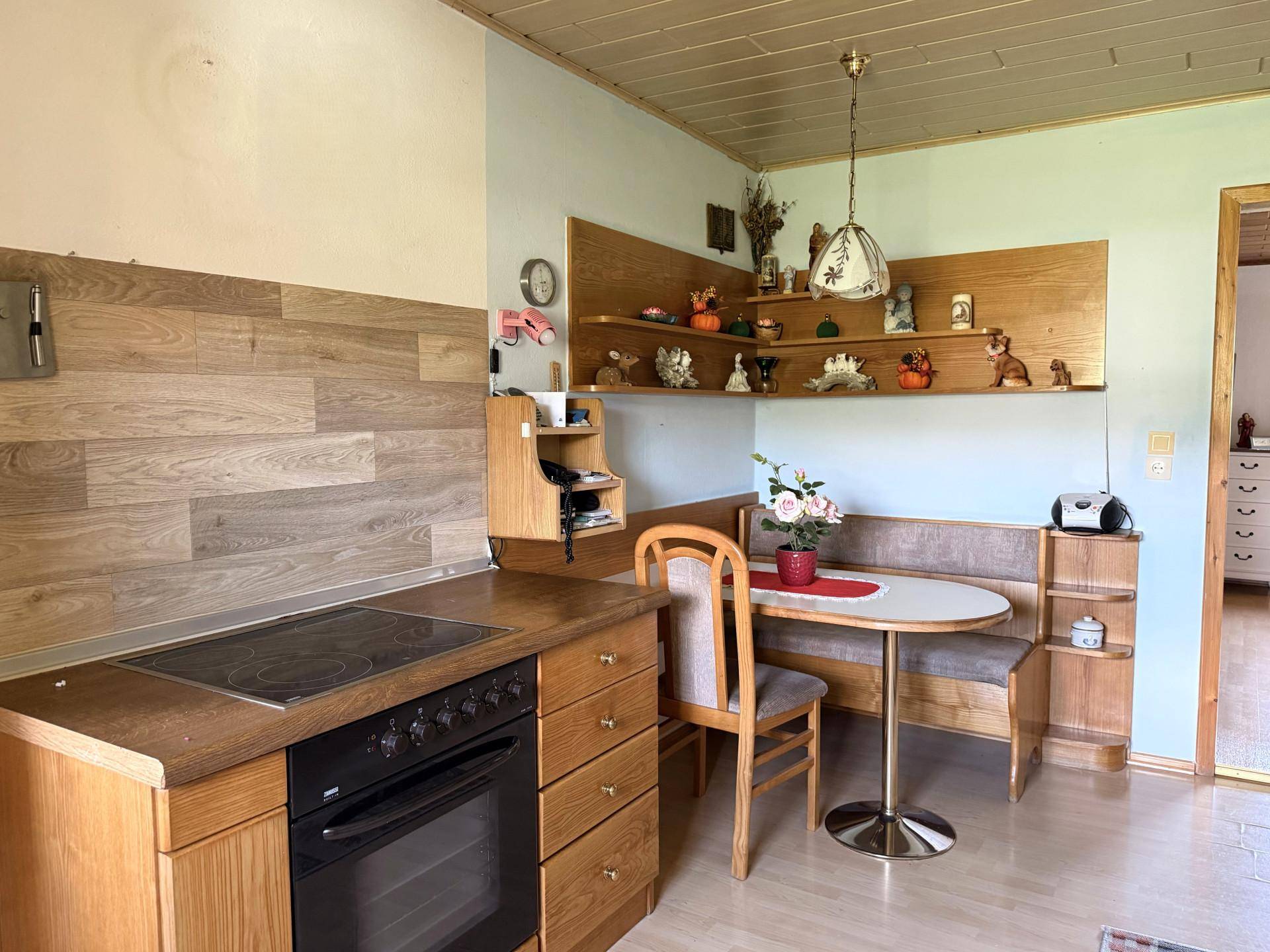 Gemütliche Wohnküche mit Holzelementen, integrierter Essecke und Blick auf die Landschaft.