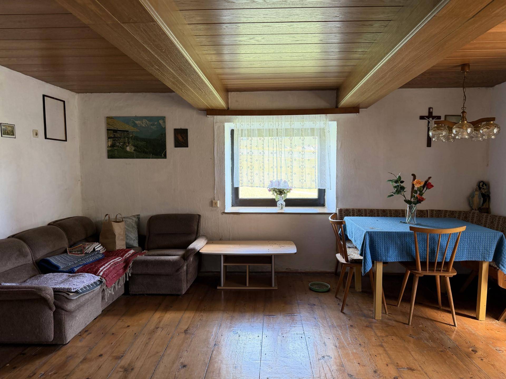 Rustikaler Wohn-Essbereich mit Holzbalkendecke, Holzboden und traditionellen Möbeln.