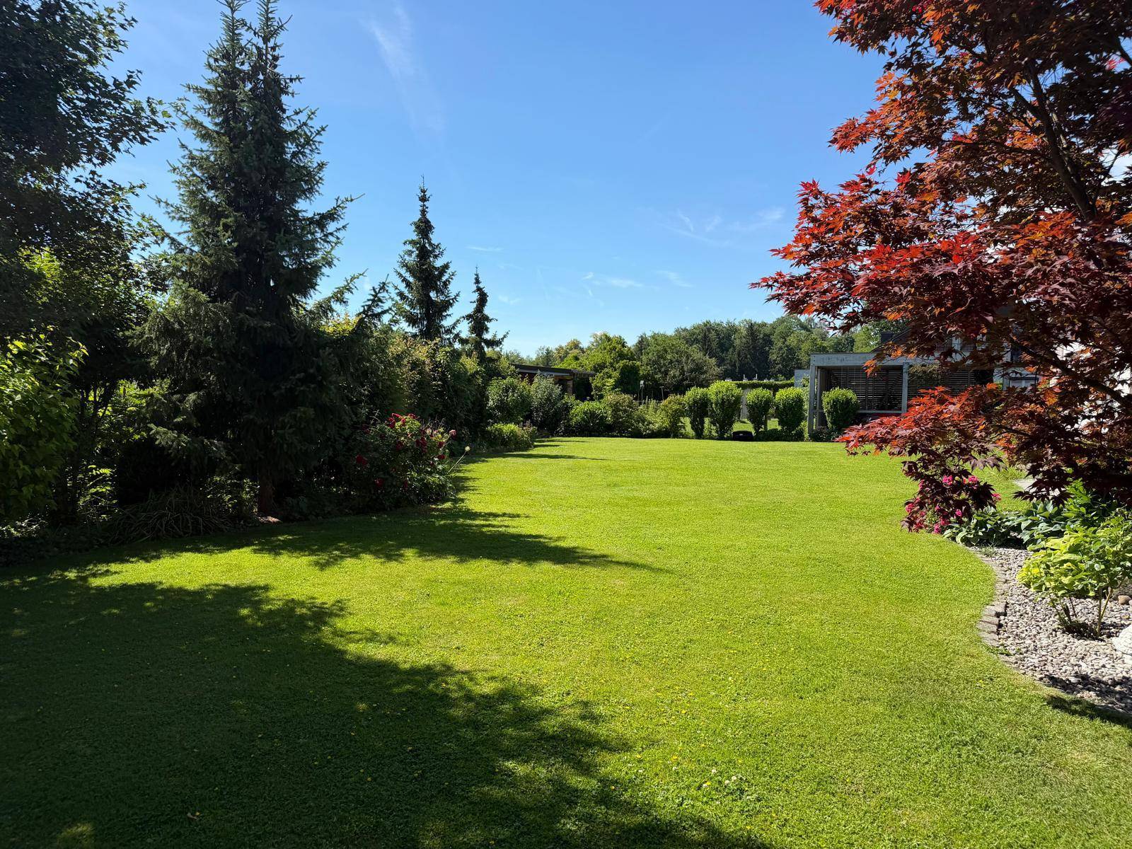 Großer, gepflegter Garten mit weitläufiger Rasenfläche, Bäumen und Sträuchern.