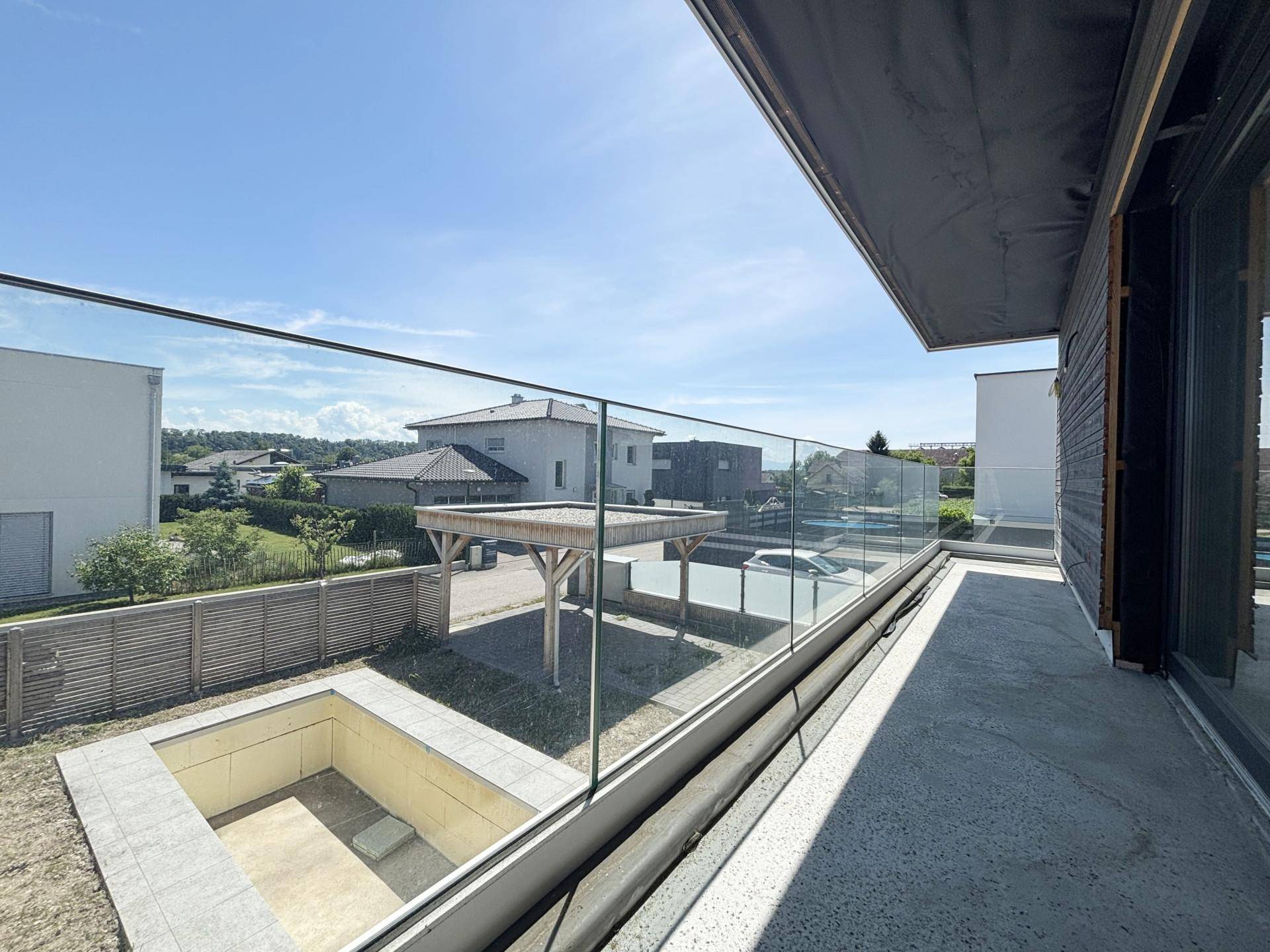 Großer Balkon mit Glasgeländer und weitem Blick über die Umgebung.