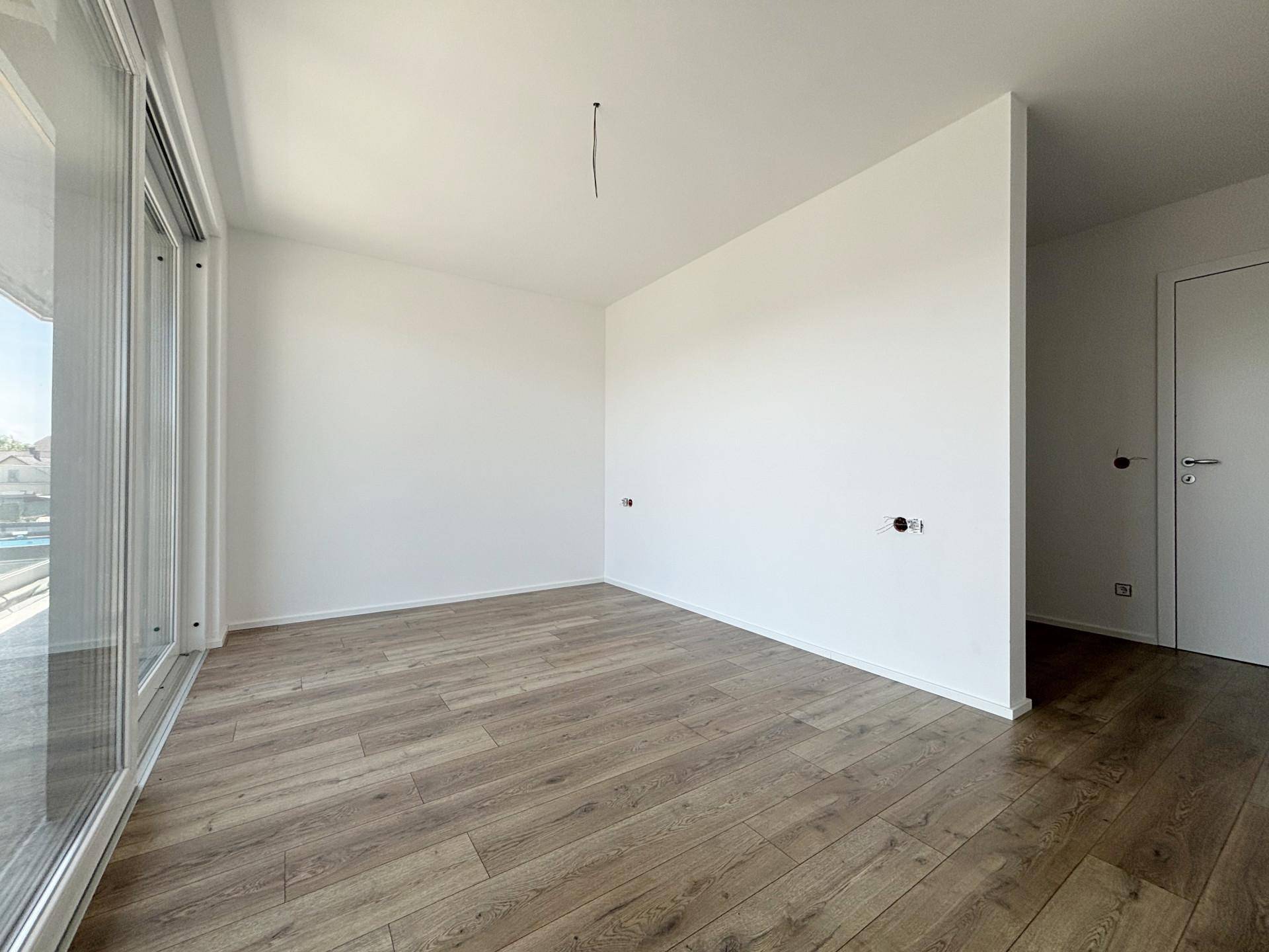 Geräumiges Zimmer mit Holzboden und großen Schiebetüren, die viel Licht spenden.