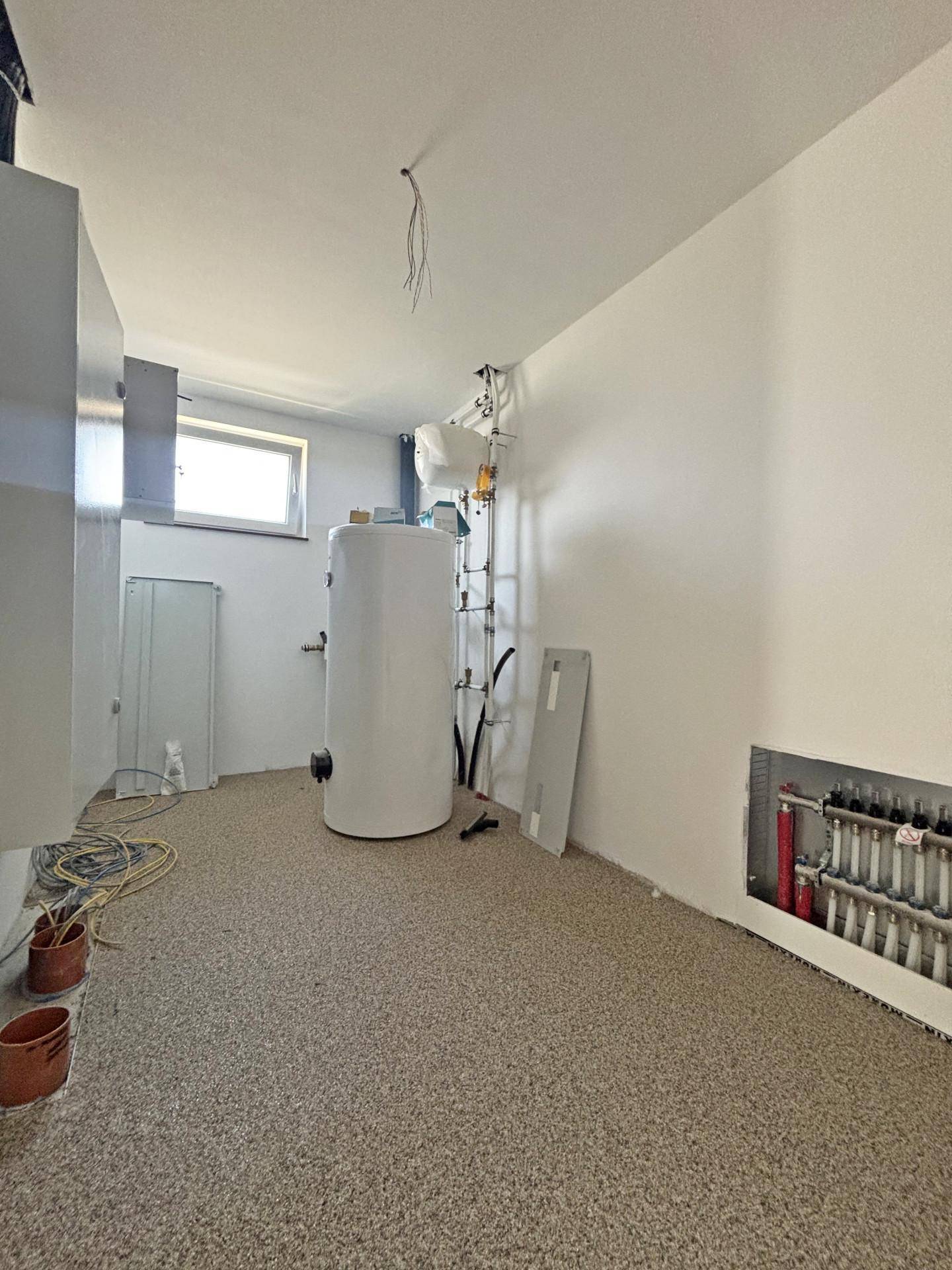 Technikraum mit Warmwasserspeicher und Heizungsverteiler, noch im Bau.