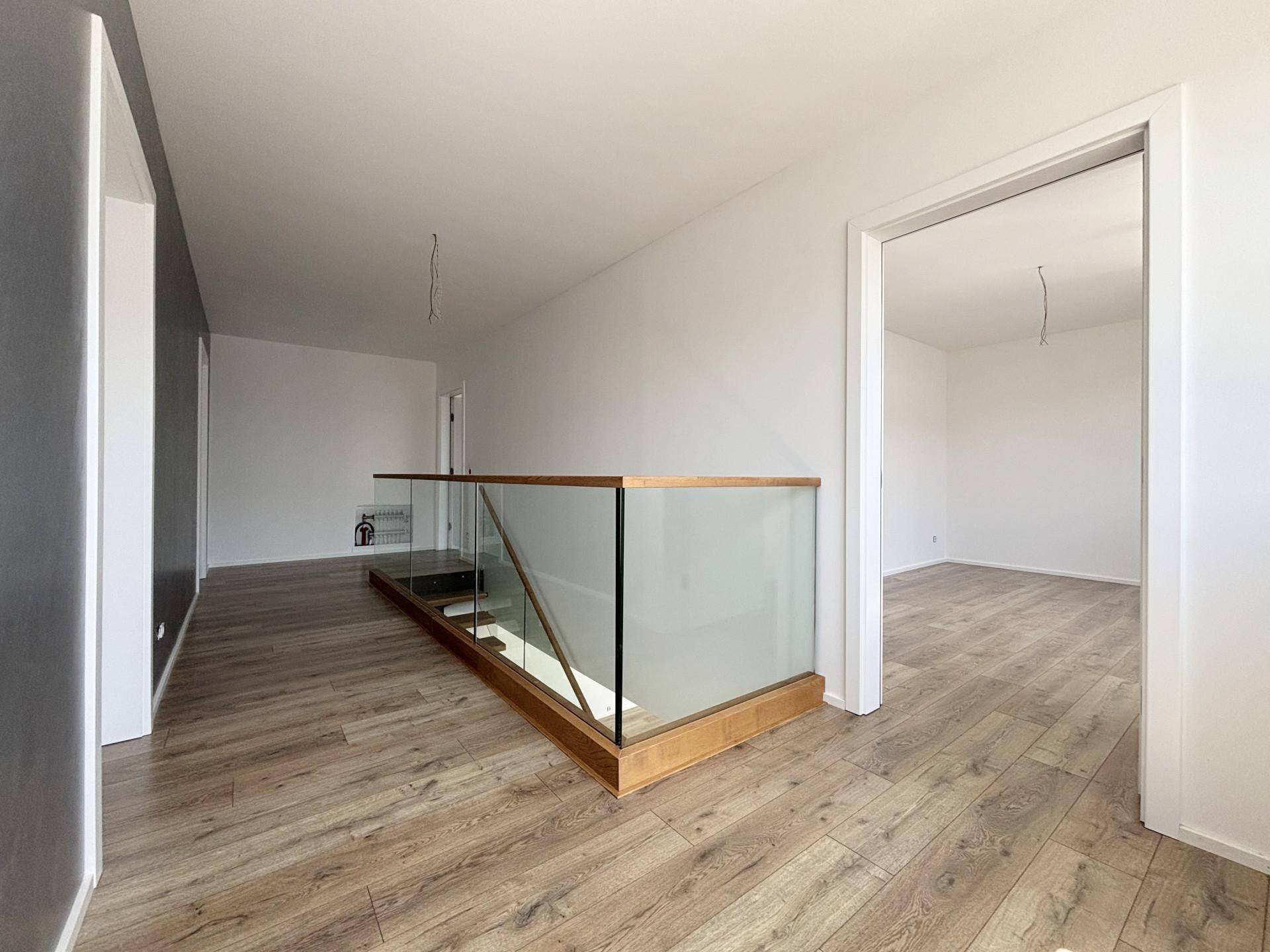 Heller Flur im Obergeschoss mit moderner Glasbrüstung und Zugang zu weiteren Räumen.