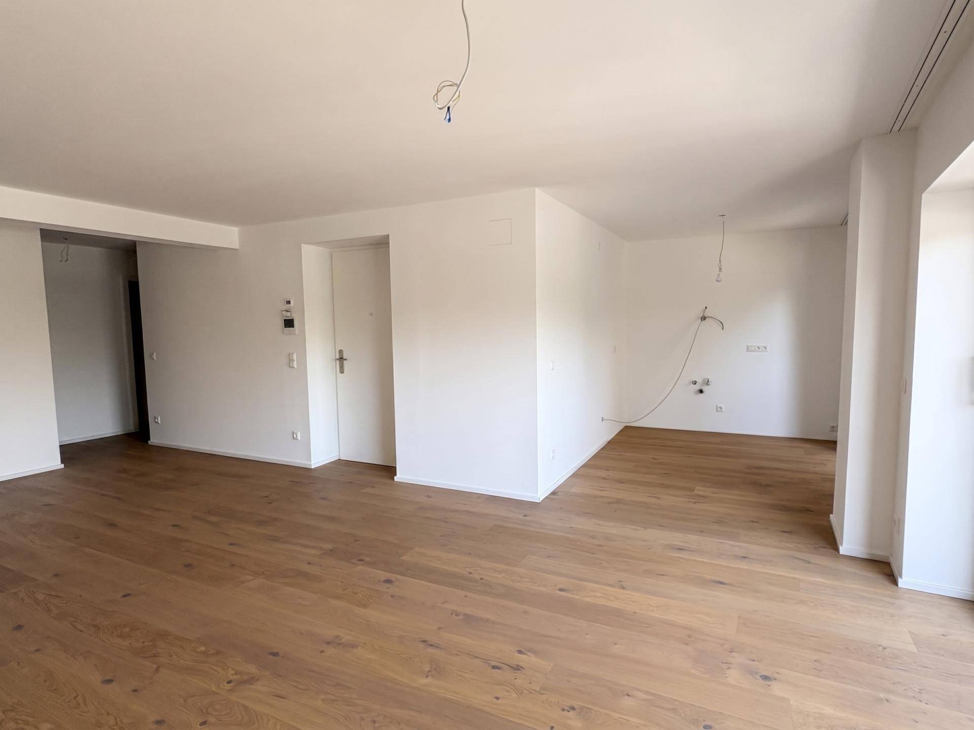 Heller, leerer Raum mit neuem Holzfußboden und weißen Wänden, bereit für die Einrichtung.
