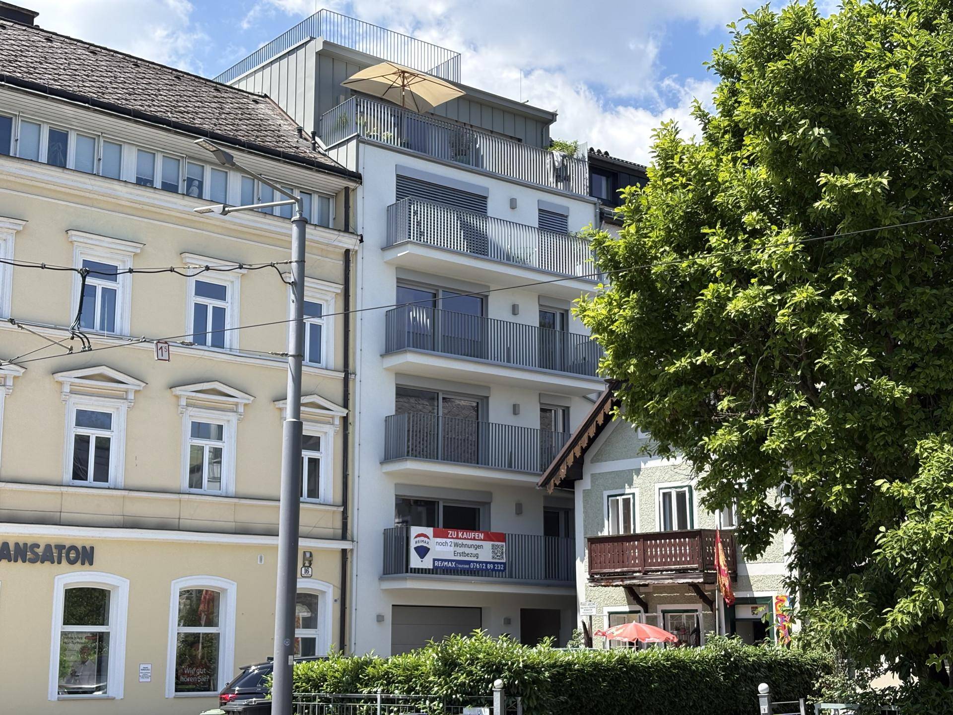 Modernes Mehrfamilienhaus mit Balkonen und großen Fenstern in städtischer Umgebung.