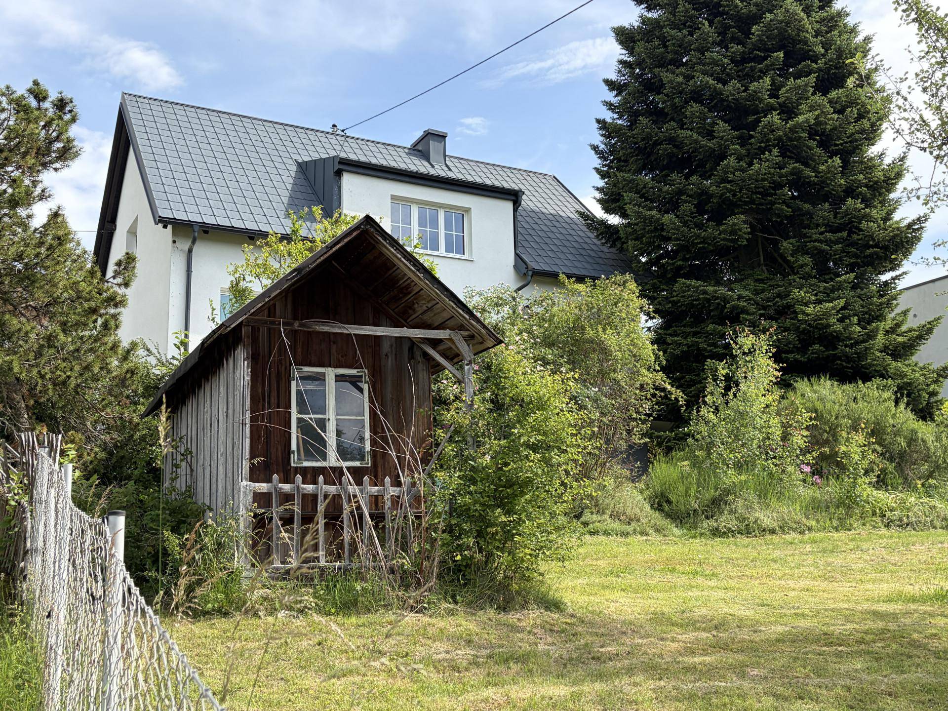 Einfamilienhaus mit Satteldach und einem kleinen Holzschuppen im weitläufigen Garten.