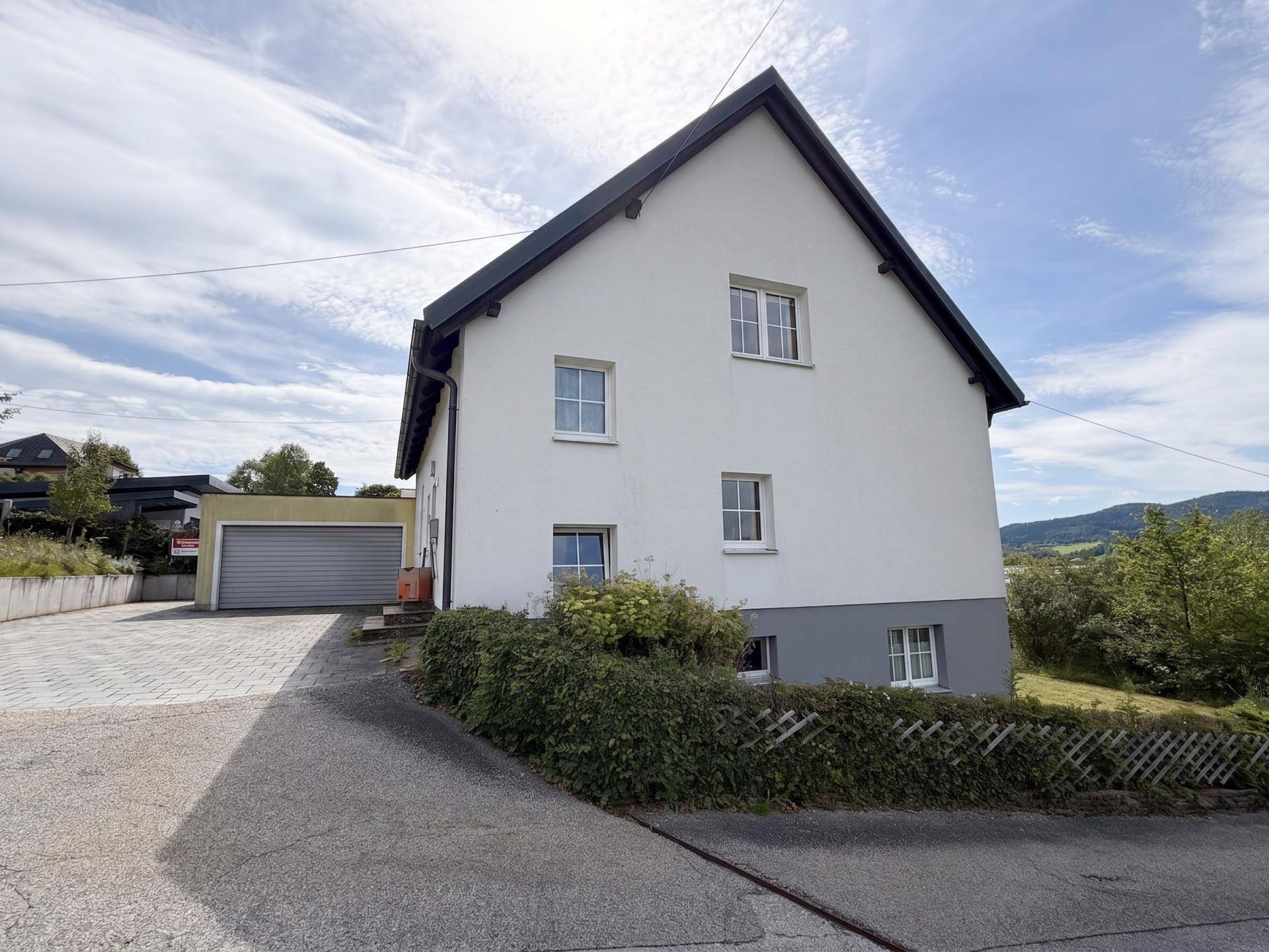 Seitenansicht des Hauses mit Zufahrt zur Garage und gepflegter Hecke im Vorgarten.
