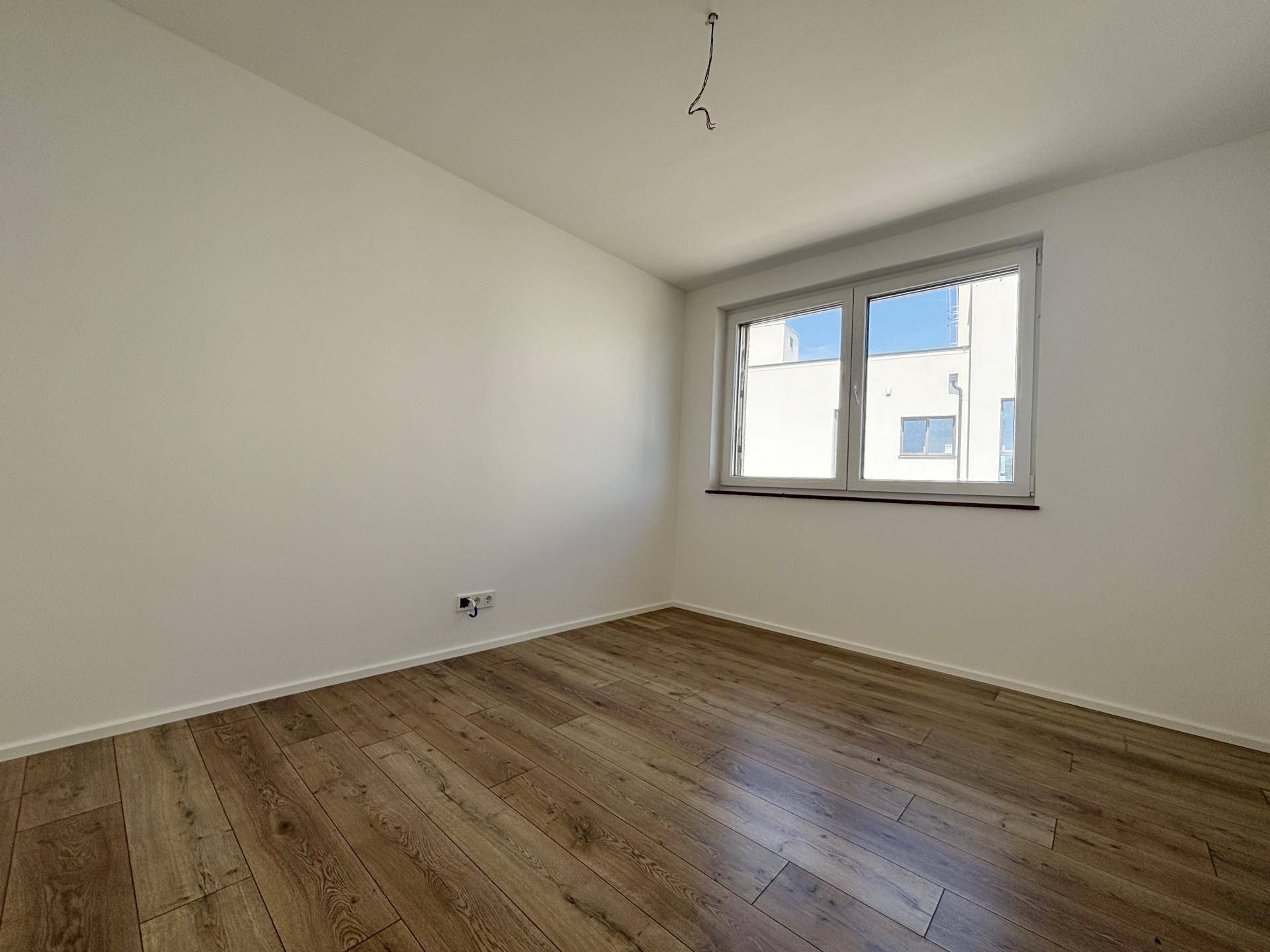 Geräumiges Schlafzimmer mit Laminatboden und großen Fenstern für viel Tageslicht.