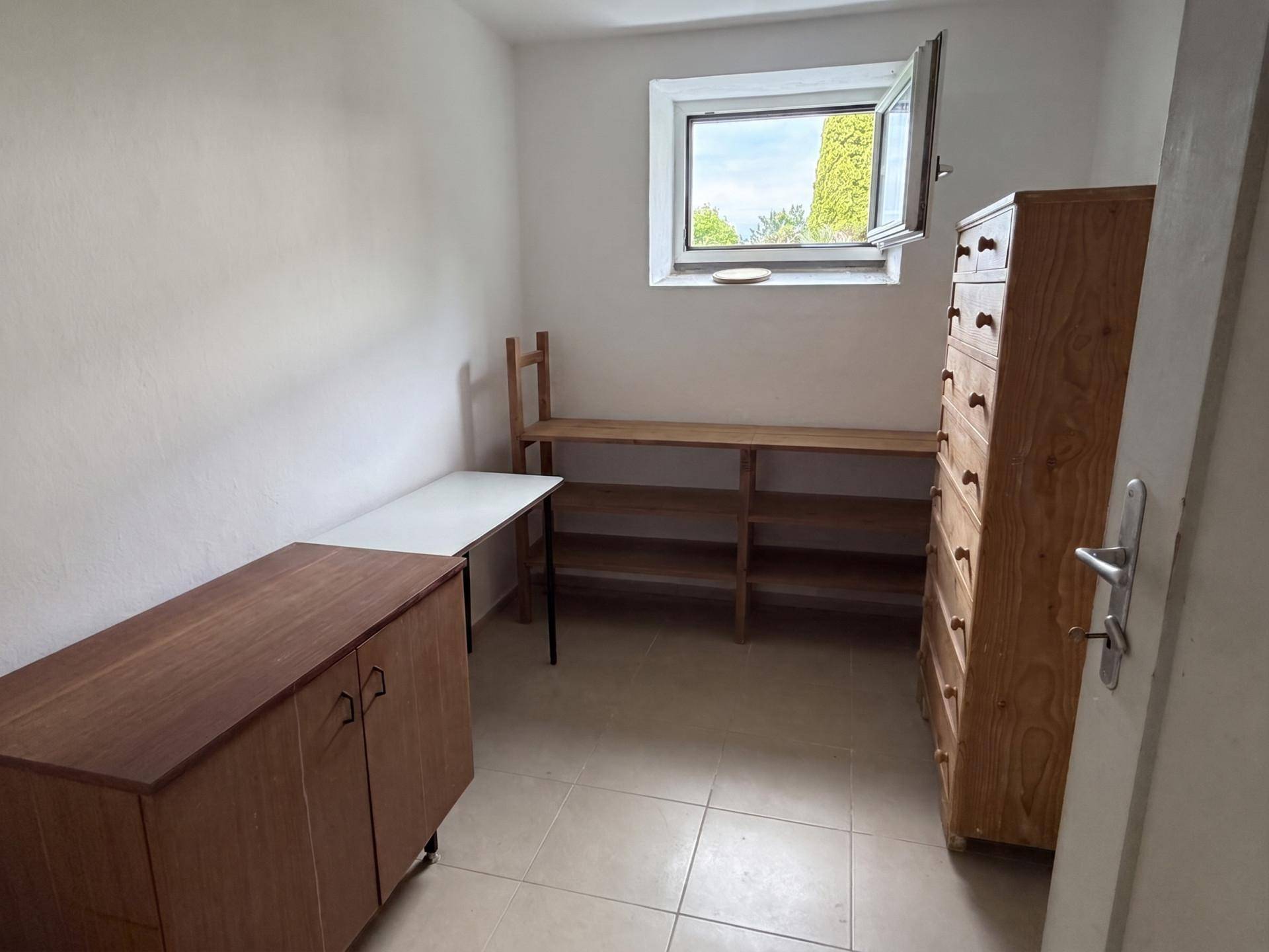 Praktischer Abstellraum mit Fenster, Fliesenboden und Regalen für Stauraum.