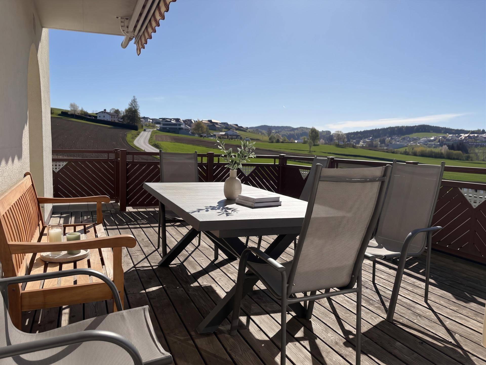 Geräumige Sonnenterrasse mit Esstisch und Stühlen, ideal für Mahlzeiten im Freien mit Weitblick.