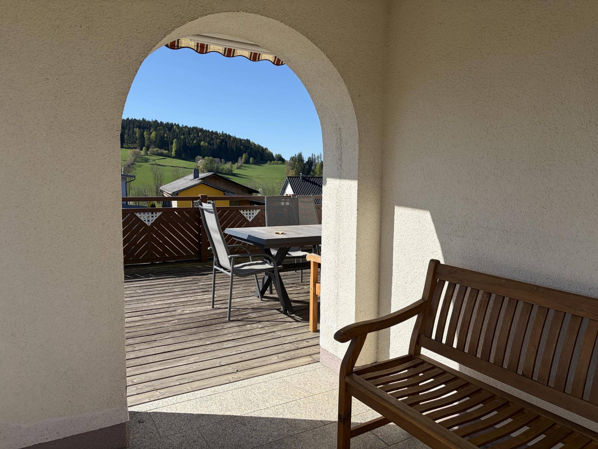 Überdachter Zugang zur Terrasse mit Holzboden und weitem Blick über die hügelige Landschaft.