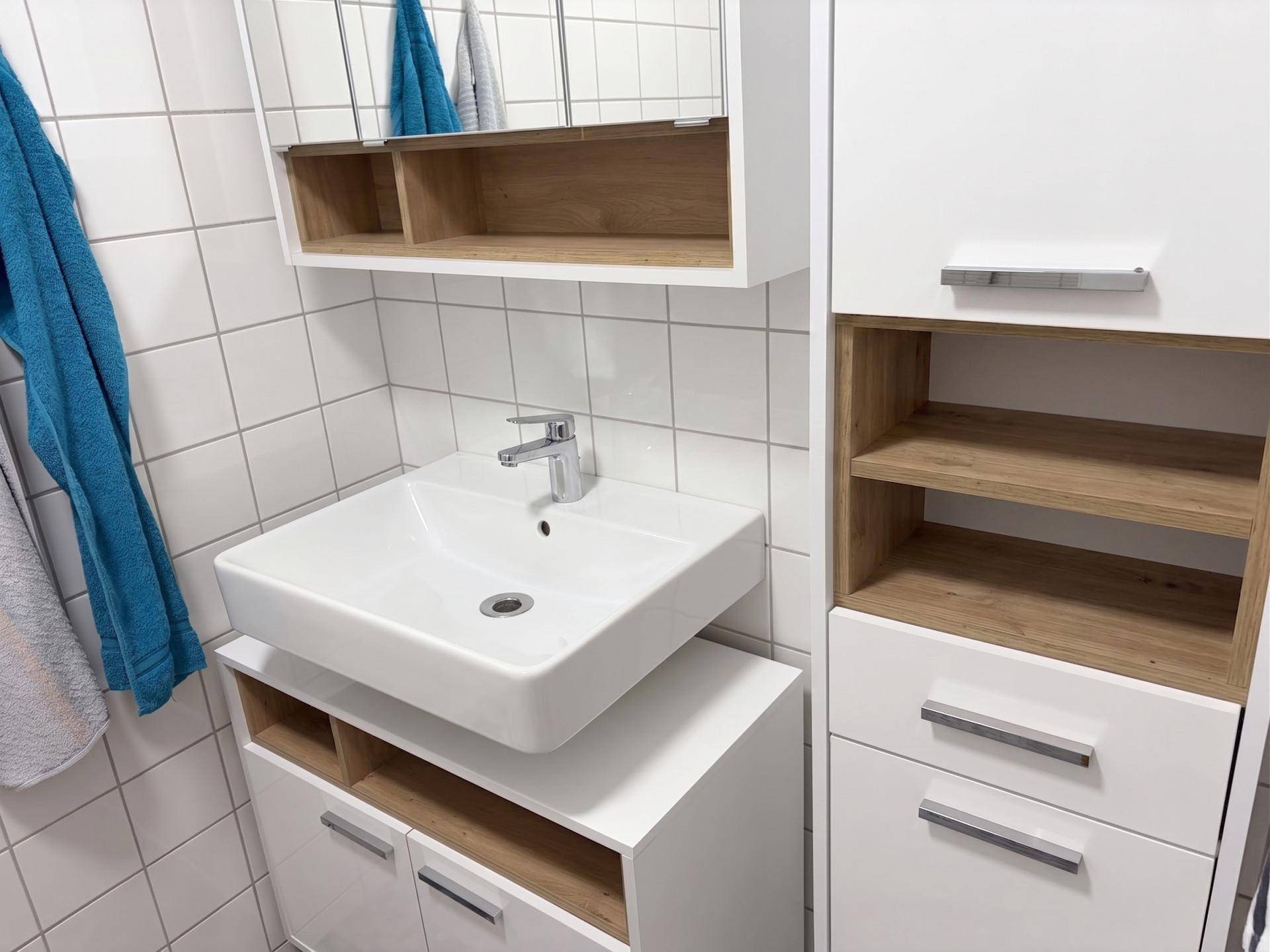 Modernes Badezimmer mit weißem Waschbecken, Spiegelschrank und hellen Fliesen.