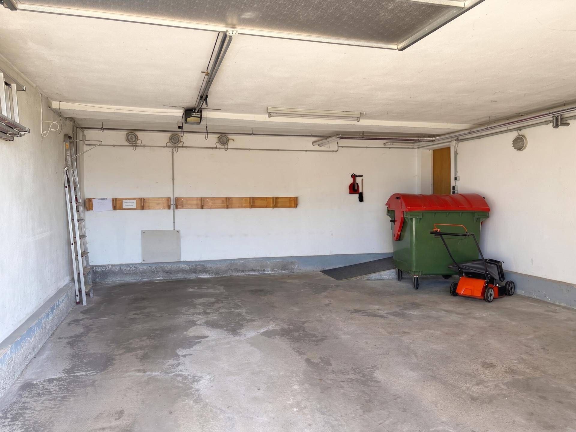 Geräumige Garage mit Betonboden, Platz für Fahrzeuge und Gartengeräte.