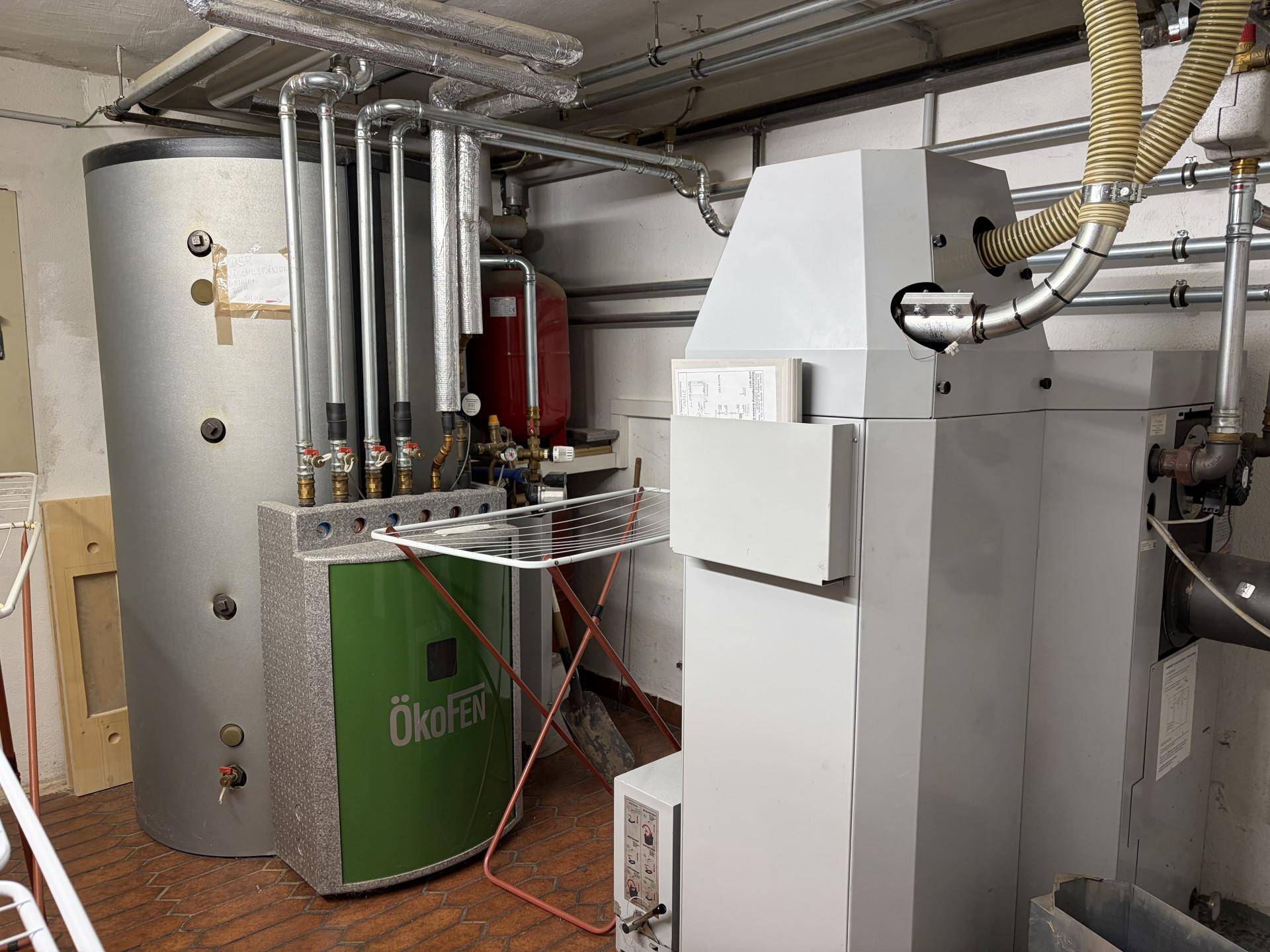Heizungsraum mit moderner Pelletheizung und Warmwasserspeicher für effiziente Energieversorgung.