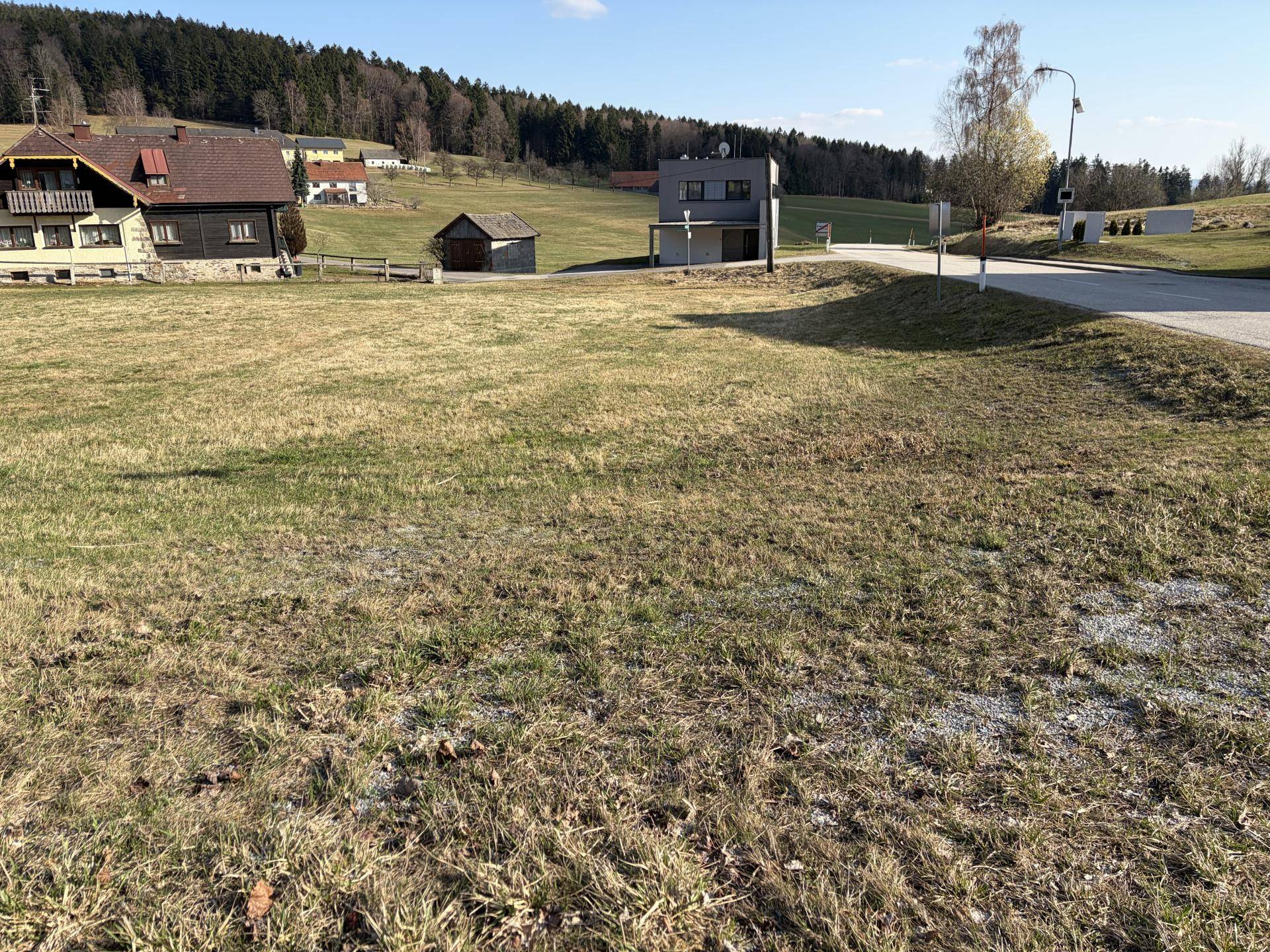 Weitläufiges Grundstück mit grüner Wiesenfläche und Blick auf die umliegende Landschaft und Häuser.