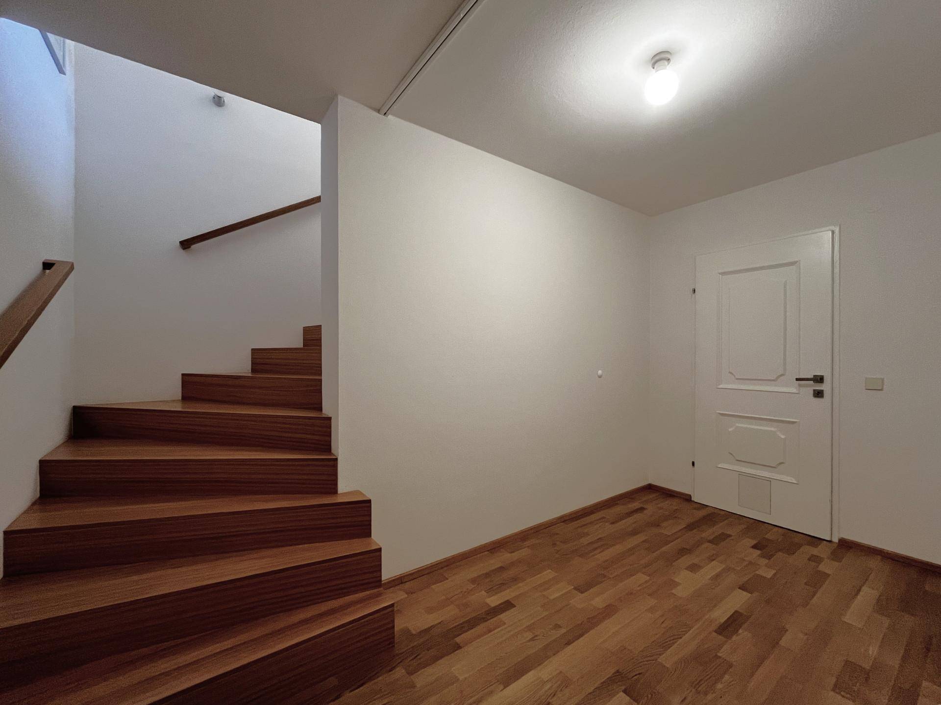 Heller Flur mit Holztreppe, die in die obere Etage führt.