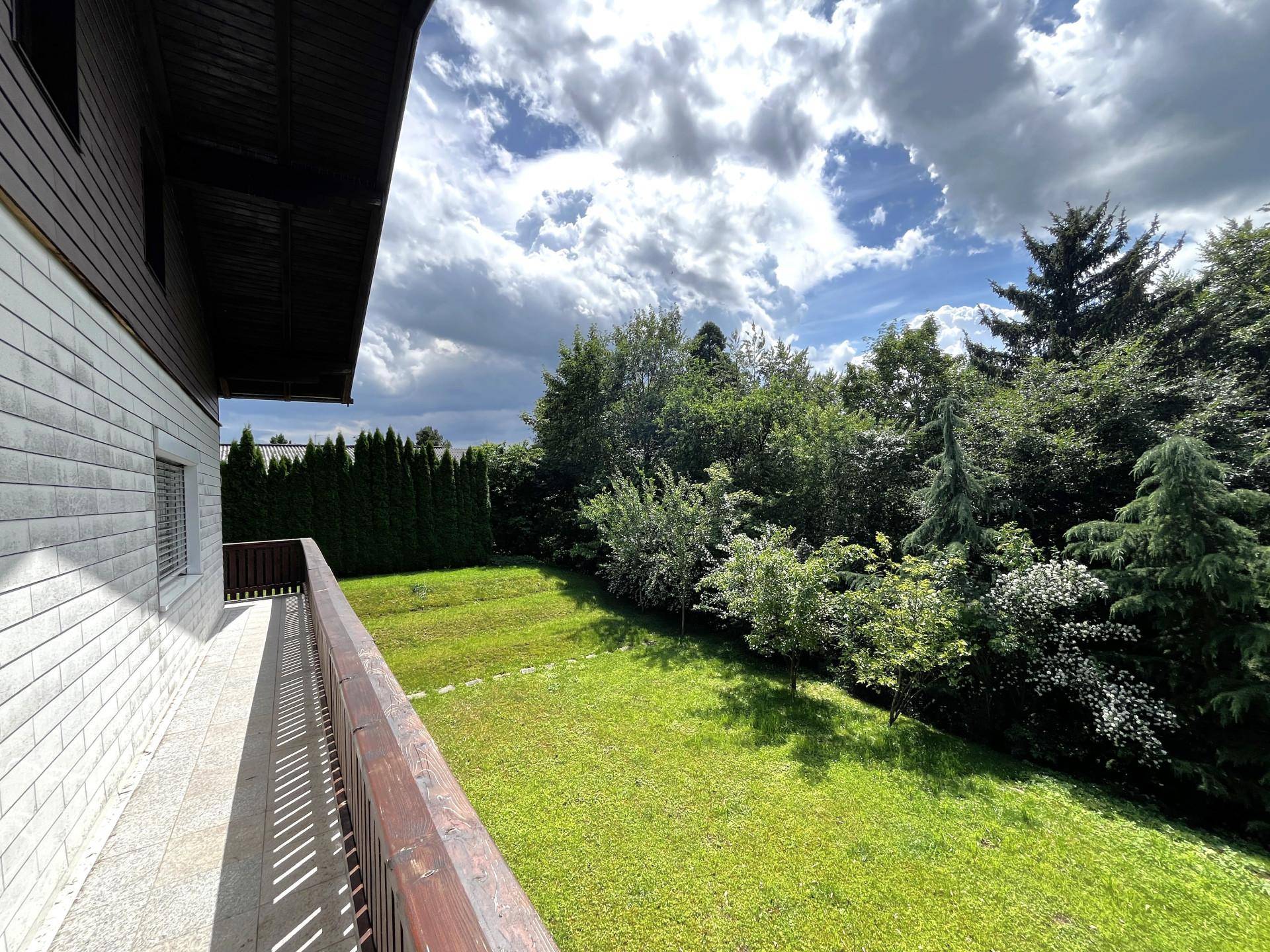 Balkon mit Holzboden und Geländer, bietet einen weiten Blick in den Garten.