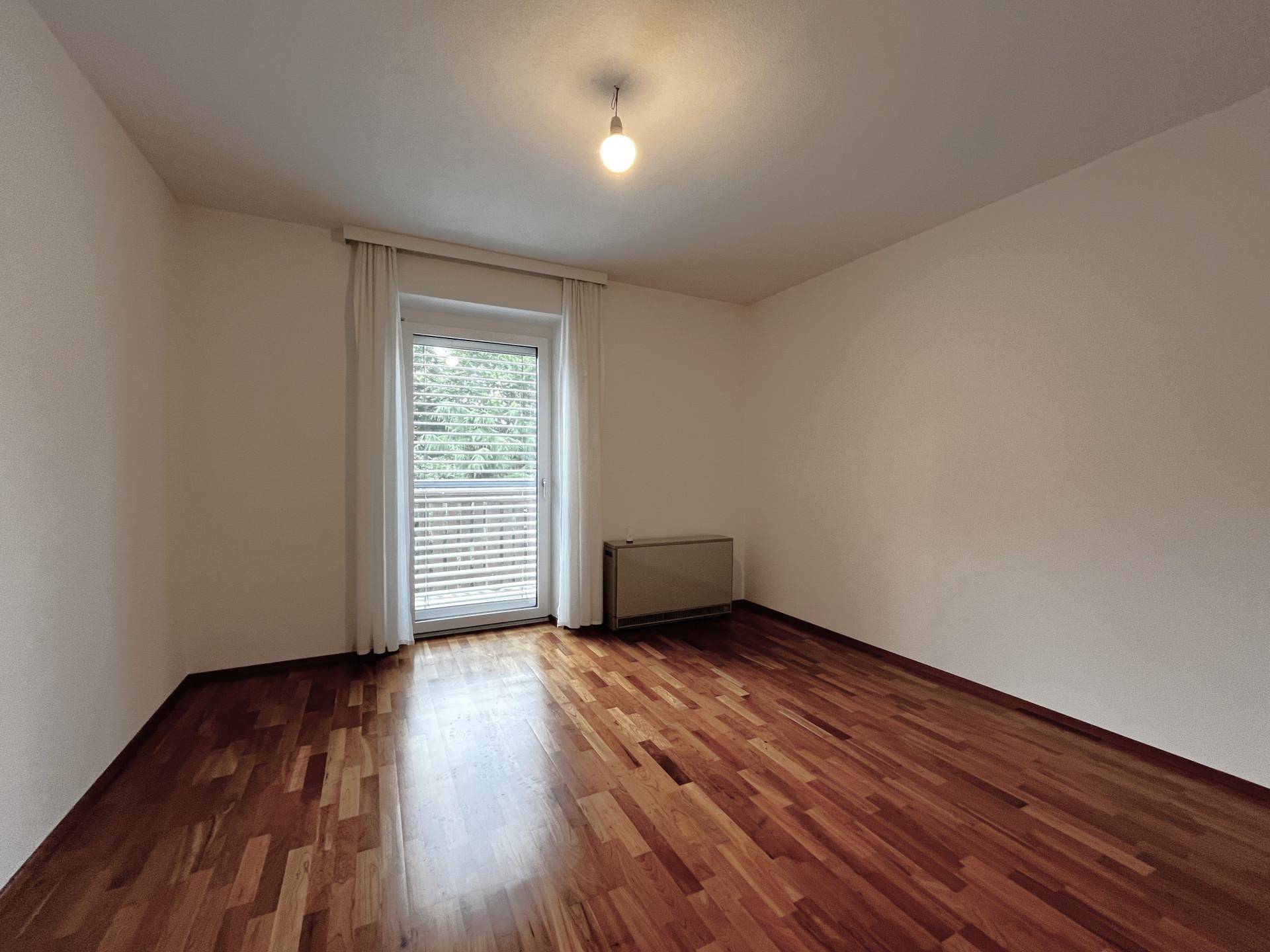 Schlafzimmer mit Holzboden und Zugang zu einem französischen Balkon.