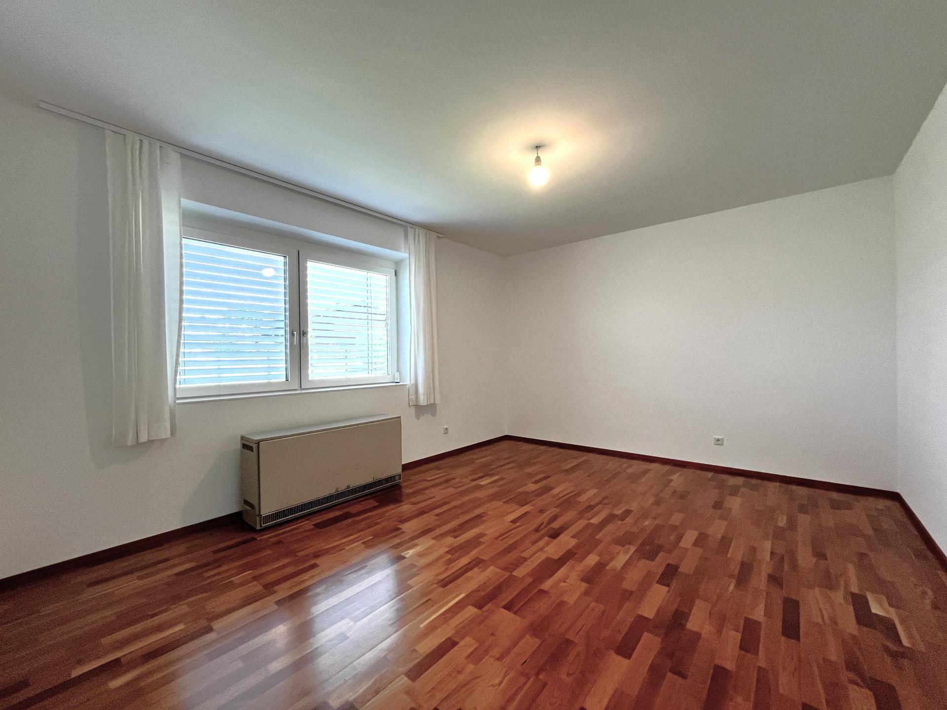 Geräumiges Schlafzimmer mit Holzboden und zwei Fenstern für viel Tageslicht.