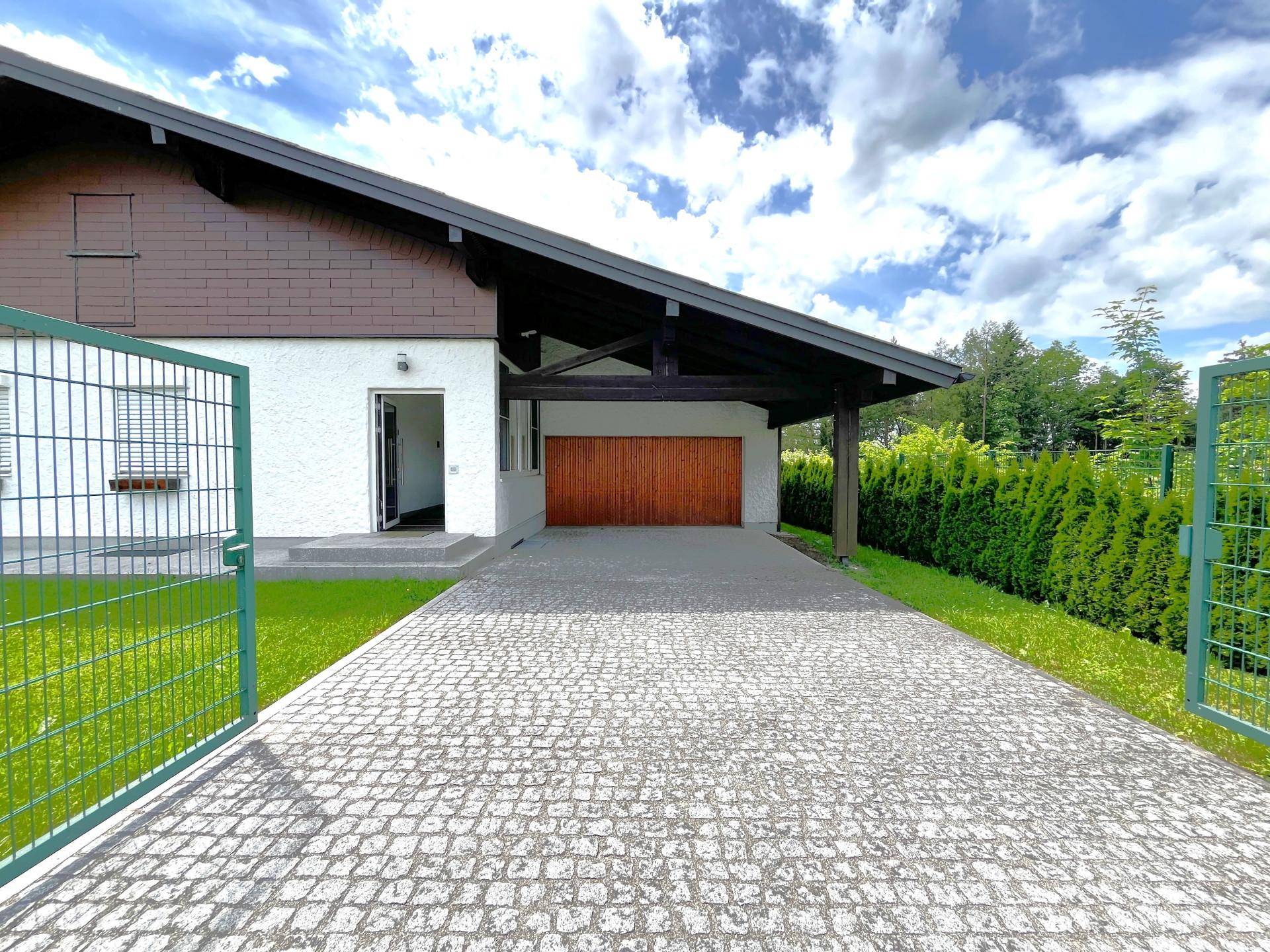 Auffahrt zum Haus mit Carport und Garage, umgeben von gepflegtem Rasen.