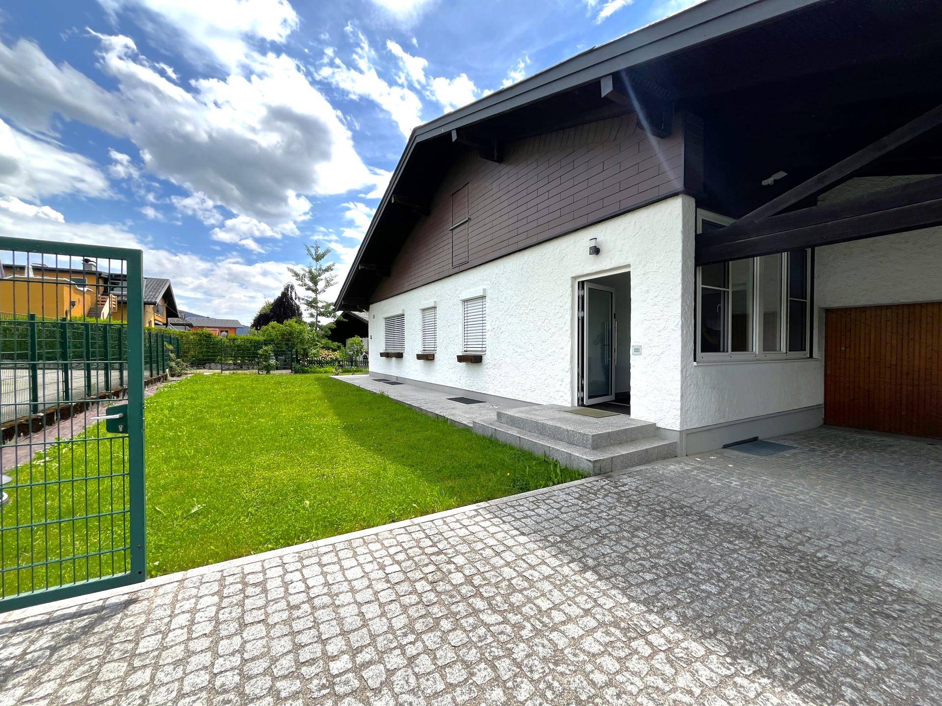 Eingangsbereich des Hauses mit gepflasterter Auffahrt und grünem Gartentor.