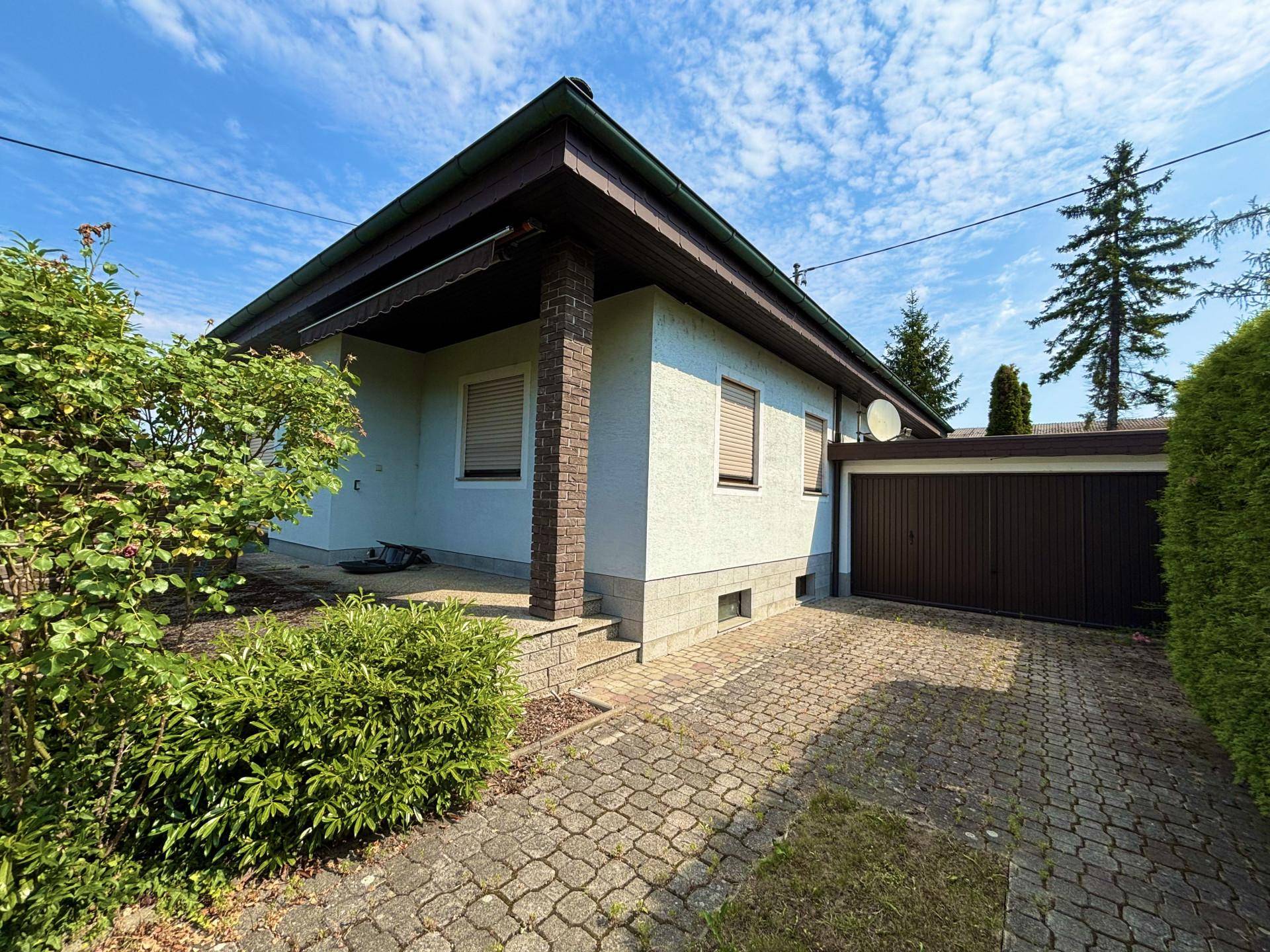 Seitenansicht des Hauses mit gepflasterter Auffahrt und integrierter Garage.