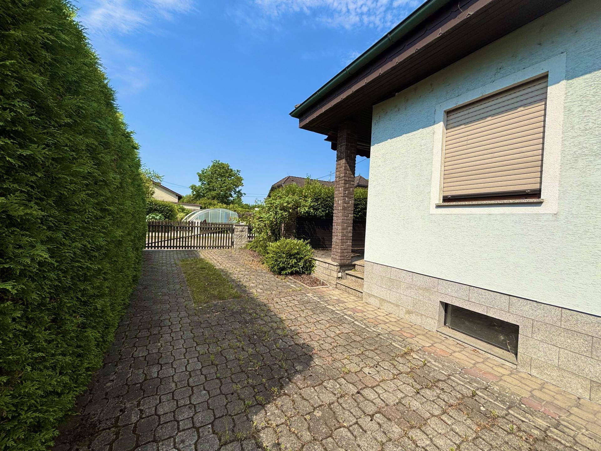 Lange gepflasterte Auffahrt entlang einer hohen Hecke zum hinteren Bereich des Grundstücks.