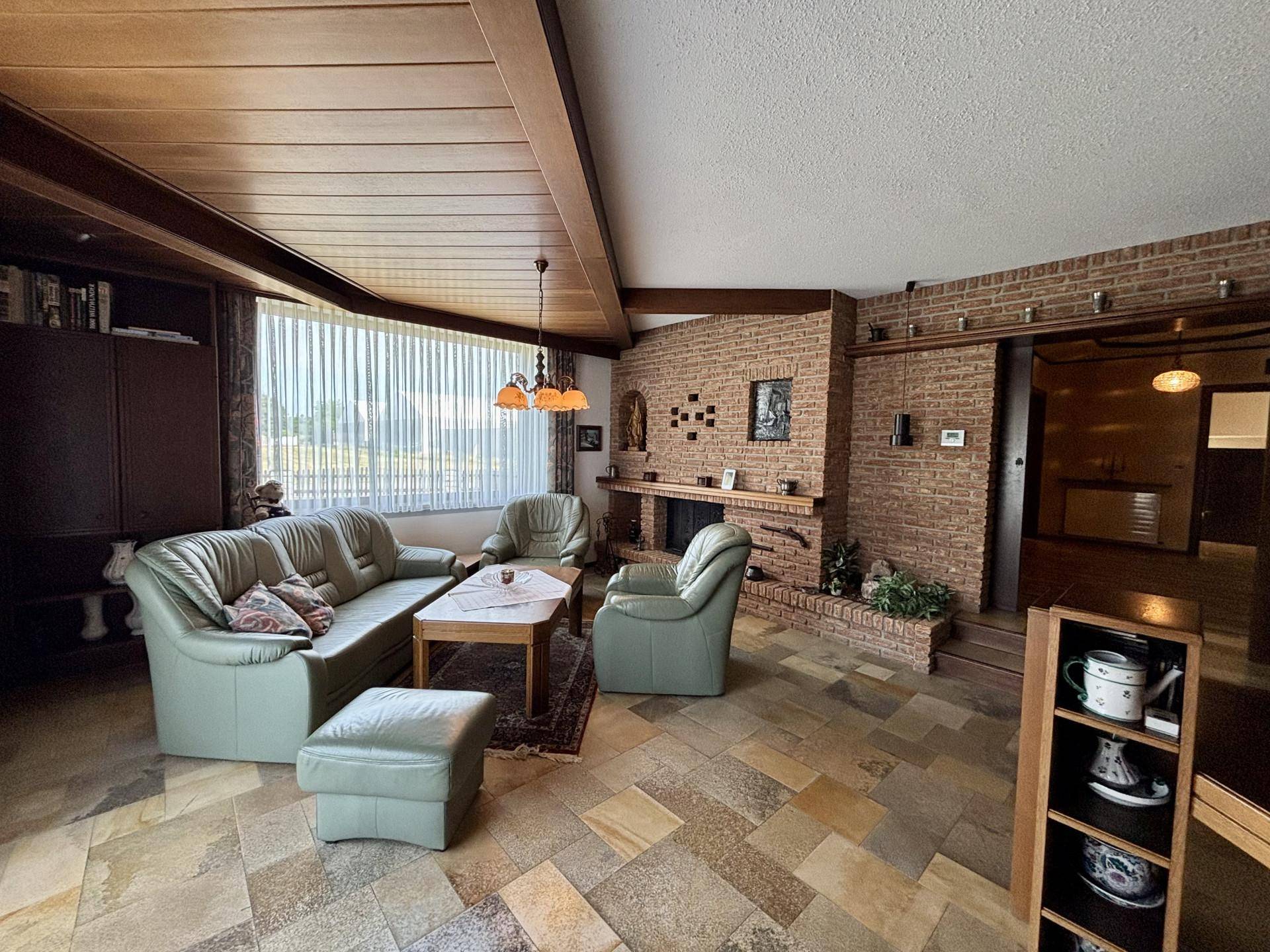 Gemütliches Wohnzimmer mit Kamin, Fliesenboden und bequemen Ledersofas.