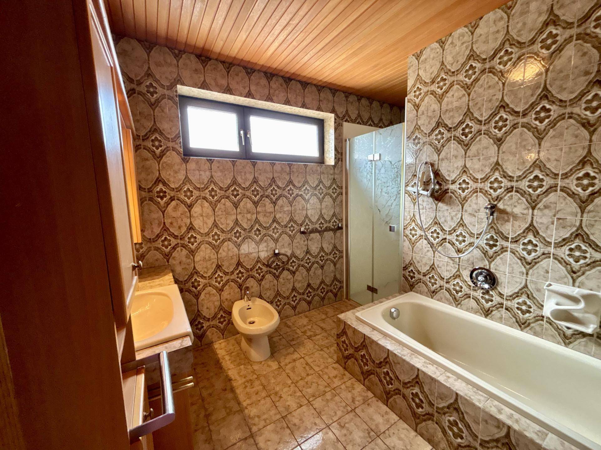 Badezimmer im Stil der 80er Jahre mit gemusterten Fliesen, Badewanne und Bidet.