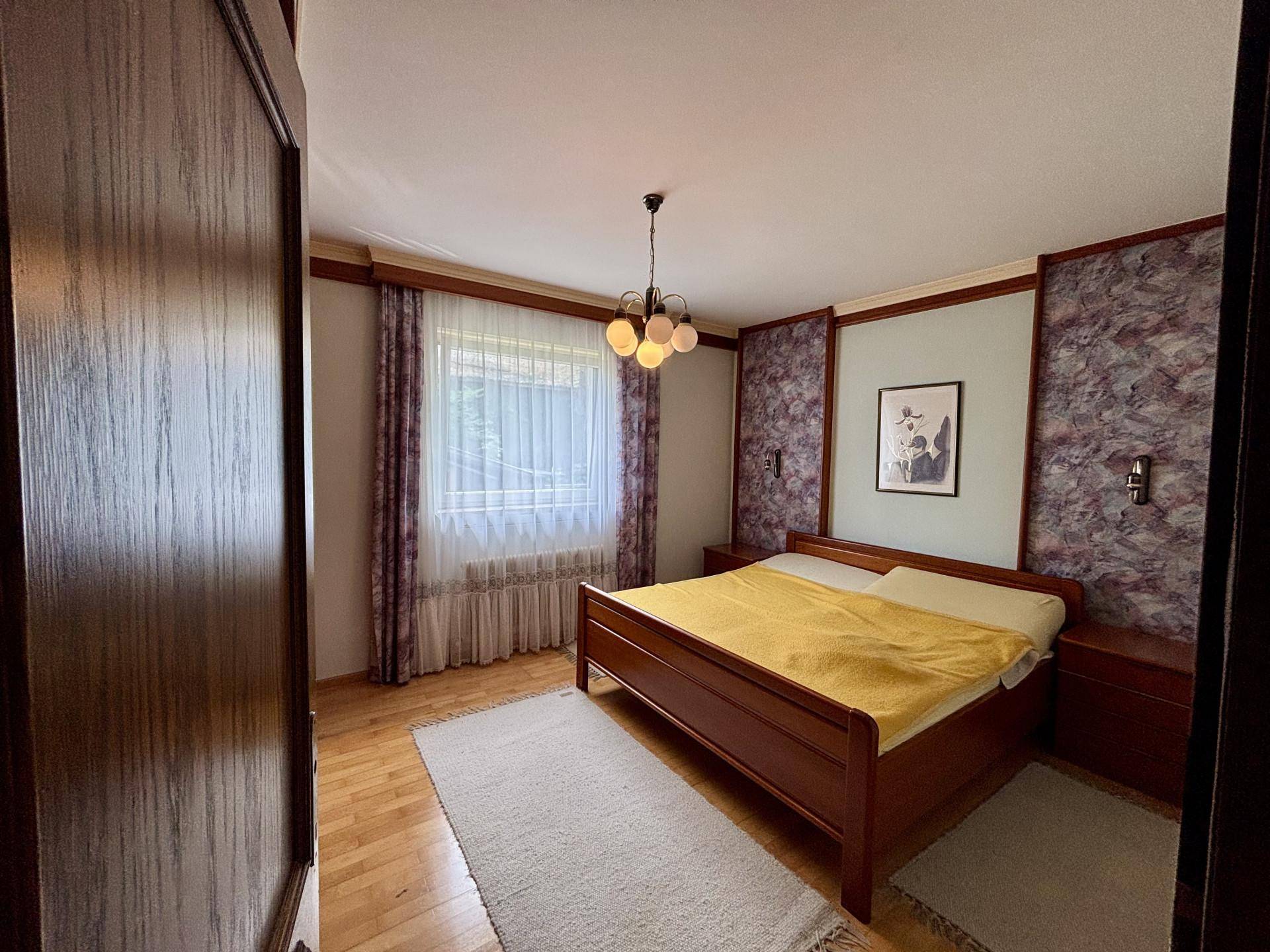 Schlafzimmer mit Holzbett, Parkettboden und dekorativer Wandgestaltung.