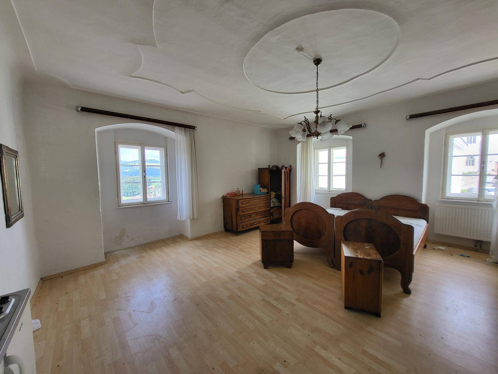 Großes Schlafzimmer mit Holzboden, Stuckdecke und traditionellen Holzmöbeln, hell und geräumig.
