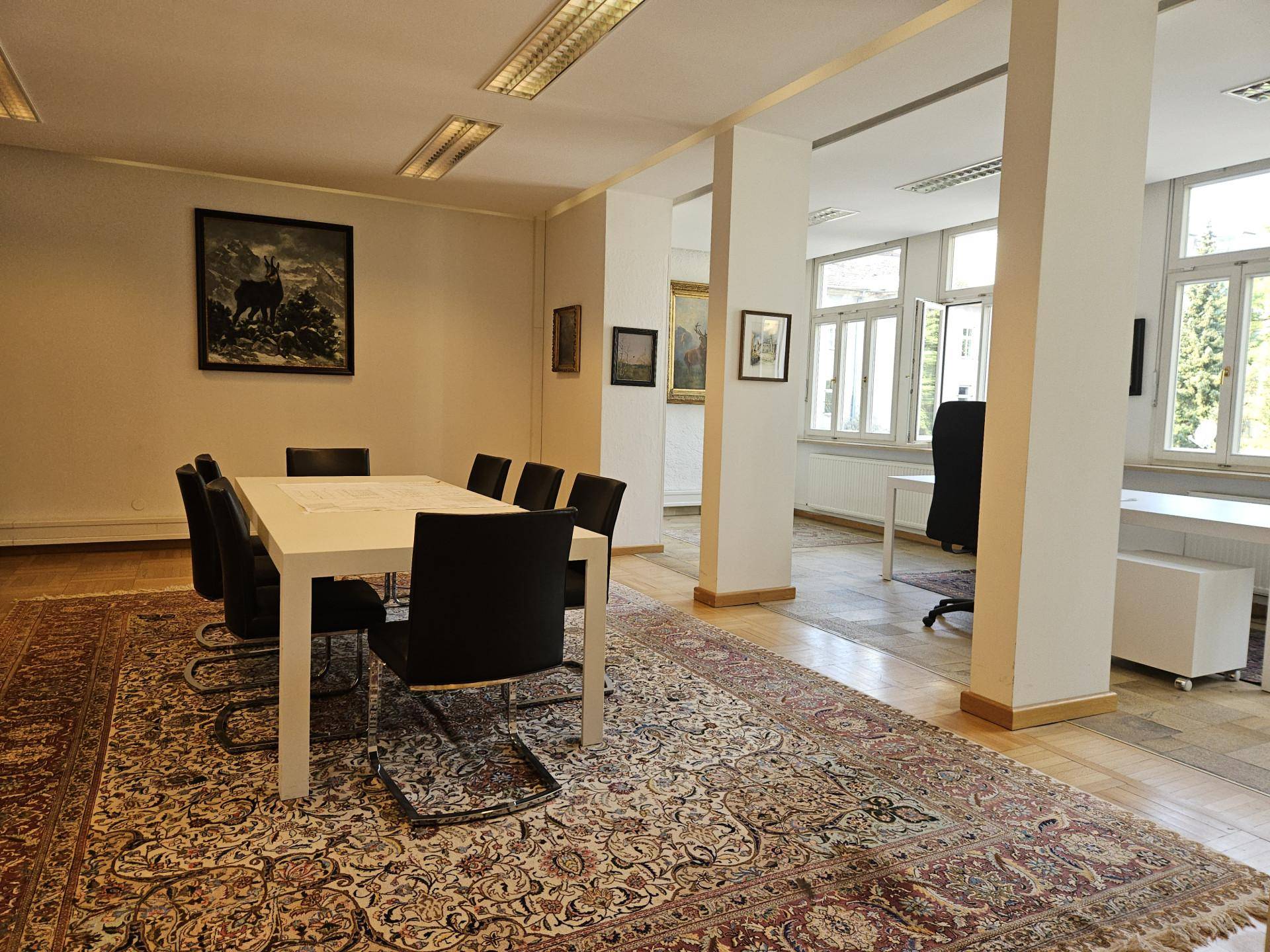 Geräumiger Konferenzraum mit großem Tisch, Säulen und Parkettboden, ideal für Besprechungen.