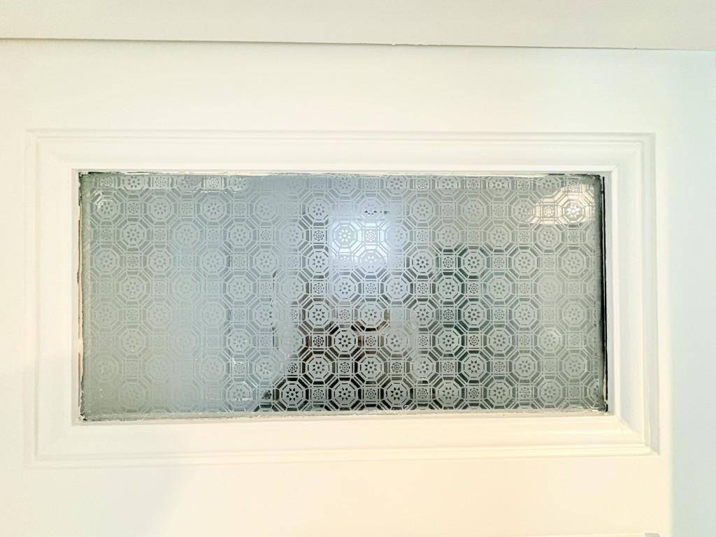 Detailaufnahme einer Tür mit gemustertem Milchglas, das für Privatsphäre sorgt.