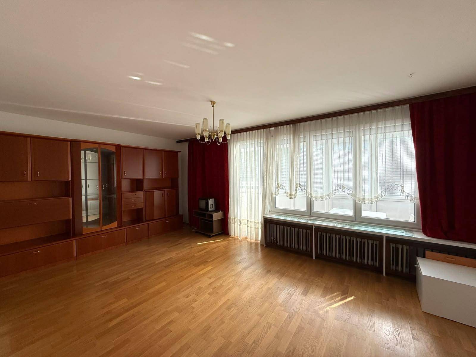 Großes Wohnzimmer mit Parkettboden, Einbauschränken und vielen Fenstern.