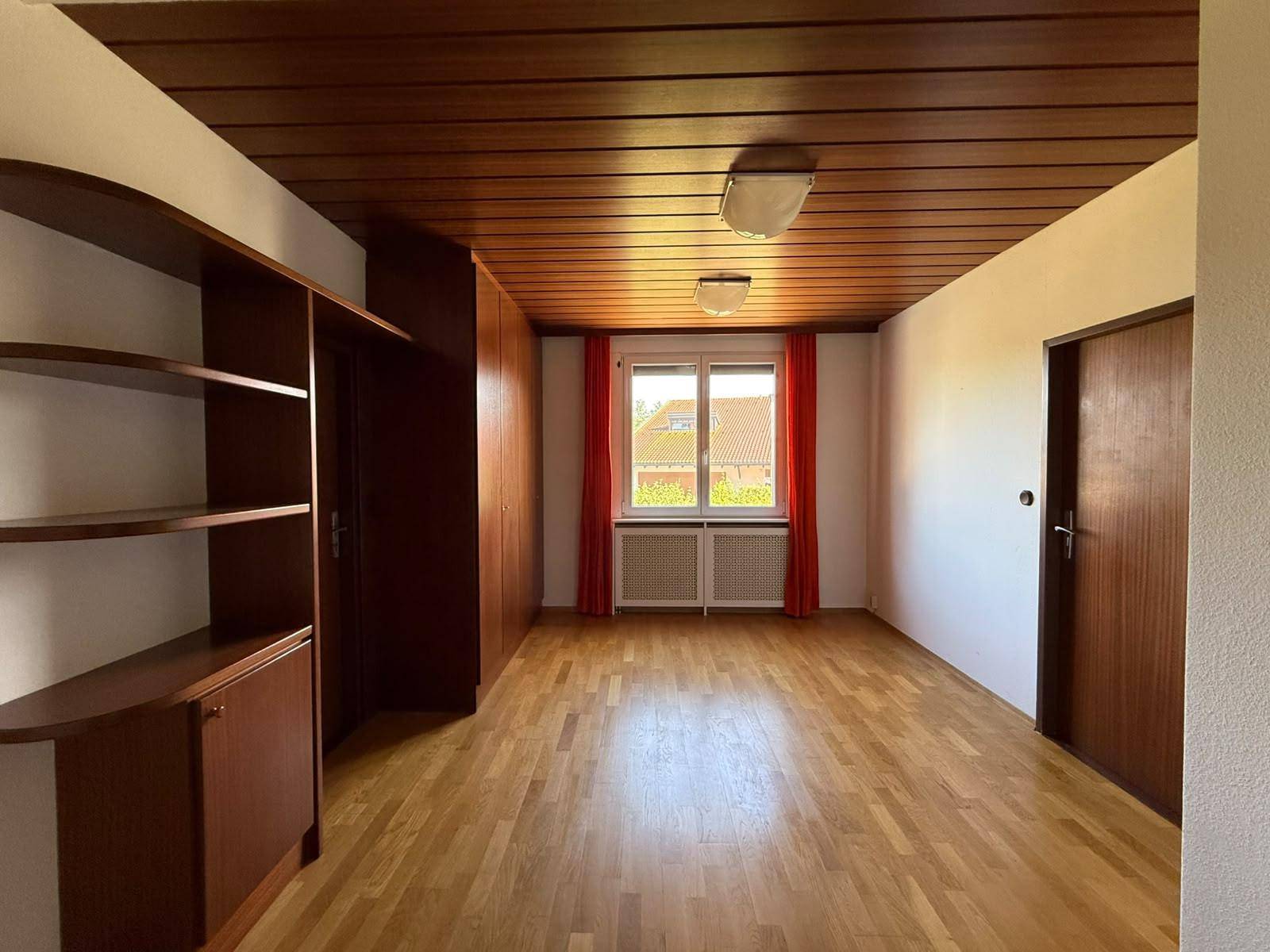 Geräumiges Zimmer mit Holzdecke, Parkettboden und Einbauschränken.