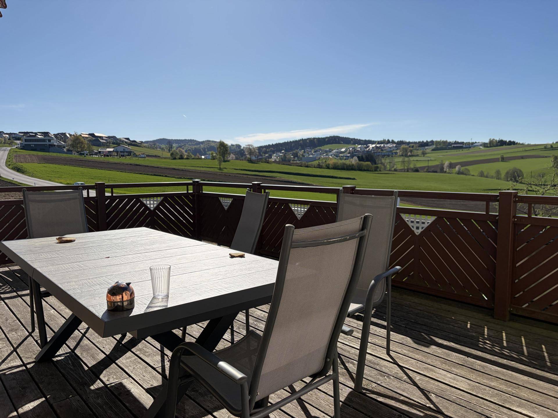 Weitläufige Terrasse mit Sitzgelegenheiten und Panoramablick auf die umliegende grüne Landschaft.