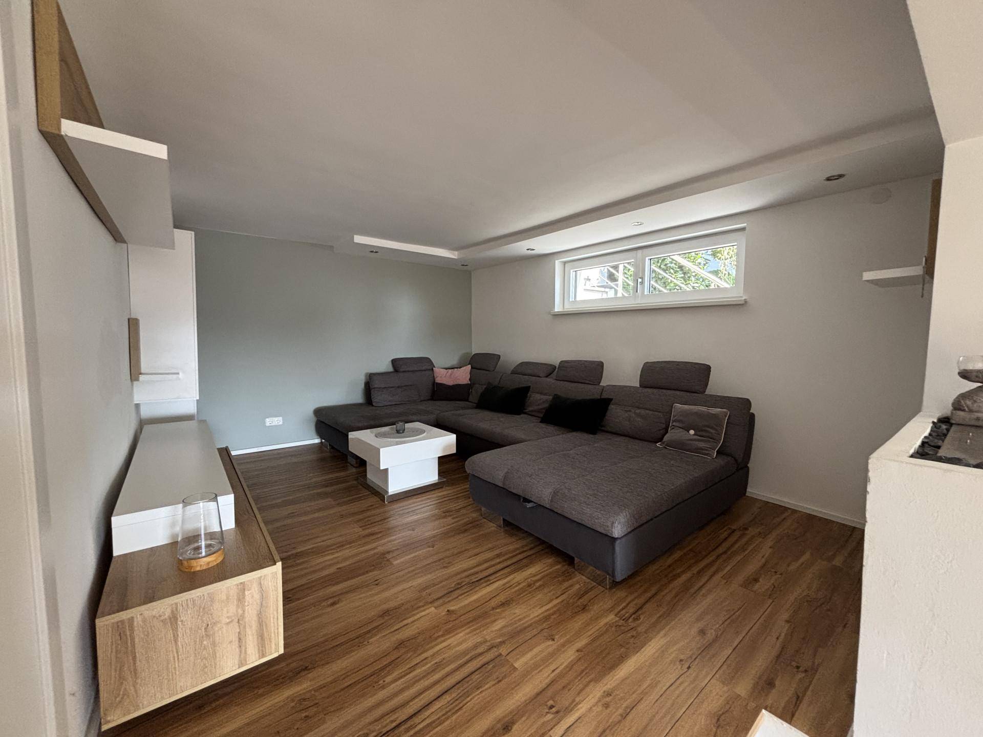 Gemütliches Wohnzimmer mit großem Ecksofa, modernem Dekor und Holzoptikboden.