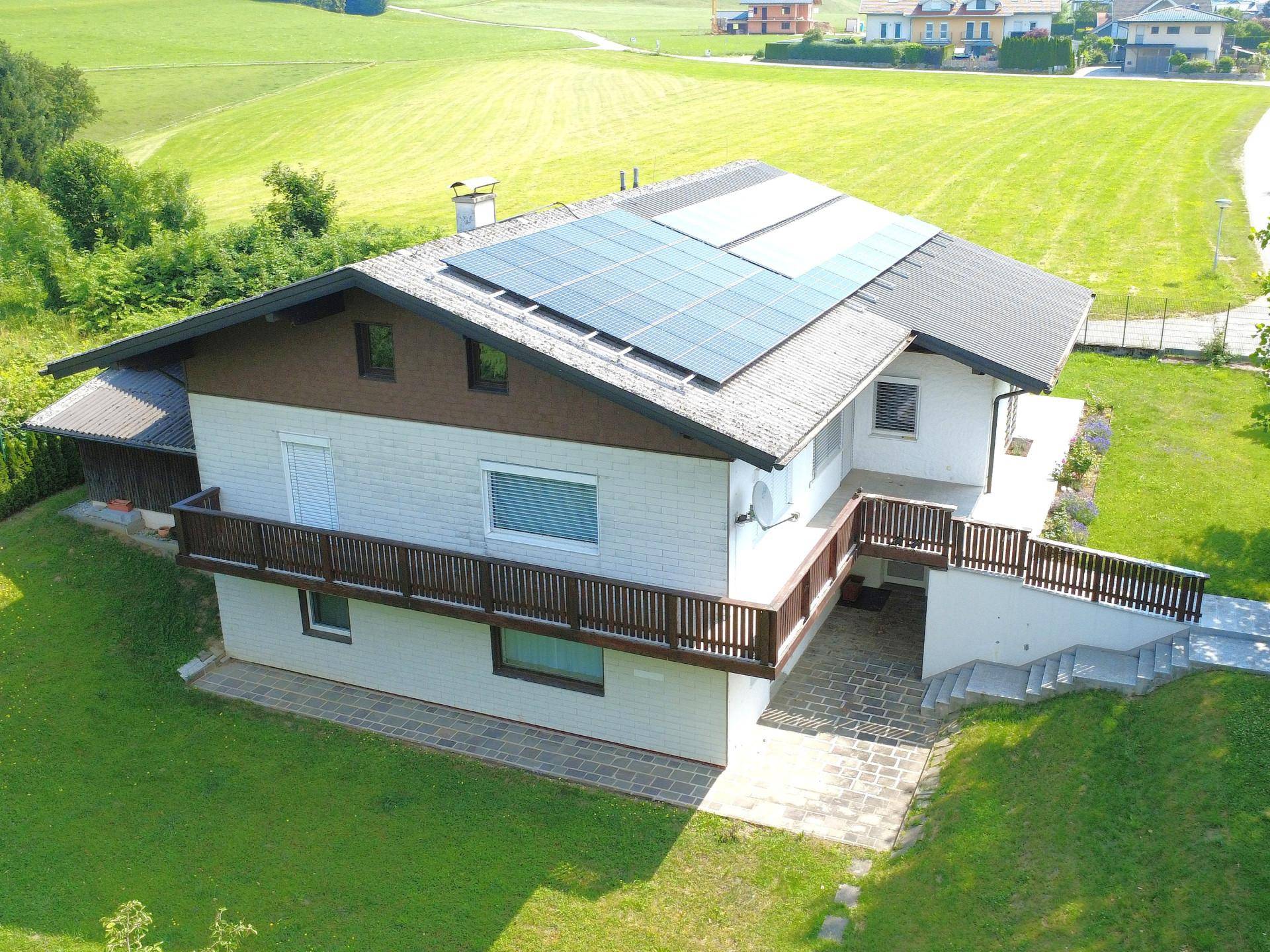 Rückansicht des Hauses mit Balkon, Terrasse und Photovoltaikanlage auf dem Dach.