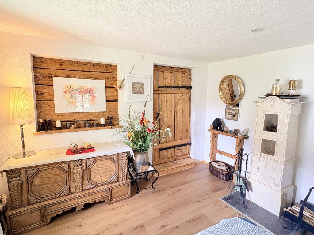 Gemütliches Wohnzimmer im Landhausstil mit Holzboden, Kachelofen und traditionellen Möbeln.
