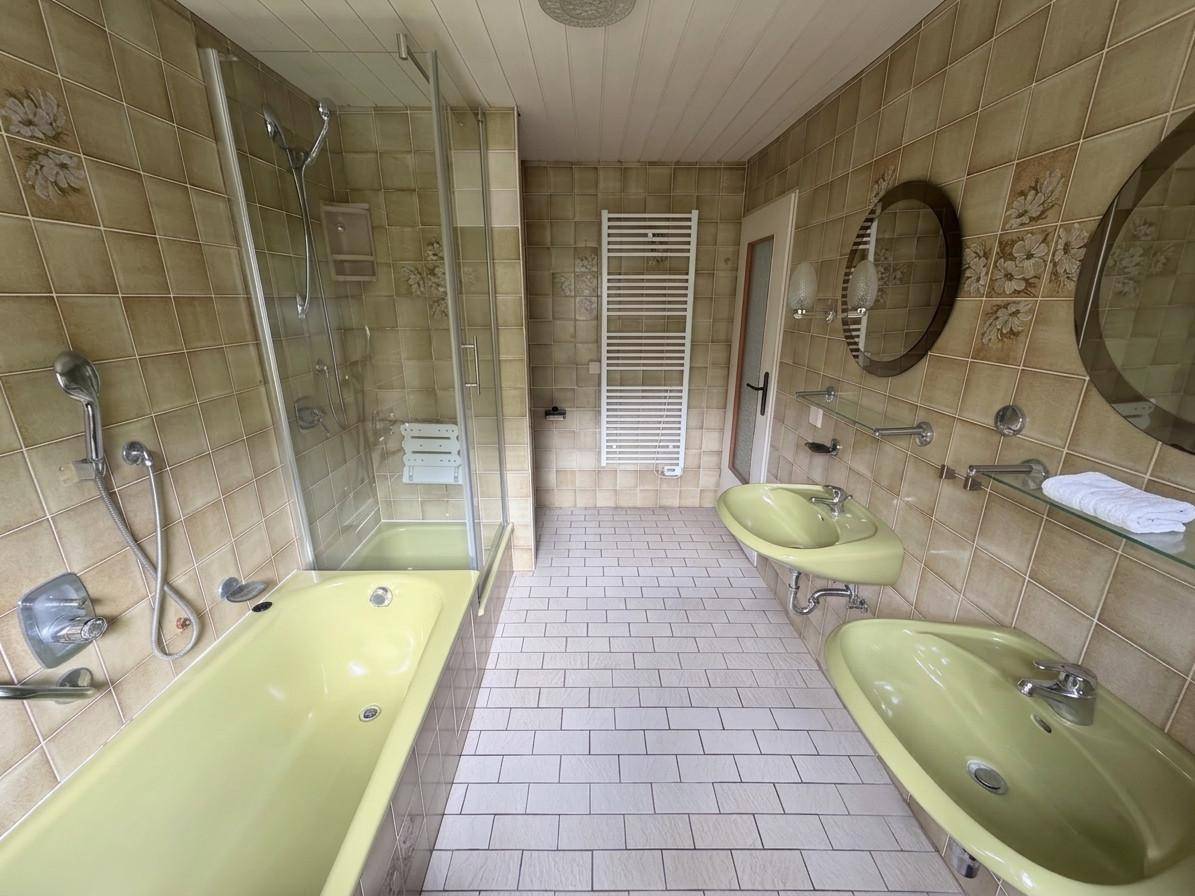 Badezimmer mit gelb-grünen Sanitärobjekten, Badewanne, Dusche und Fliesenboden.