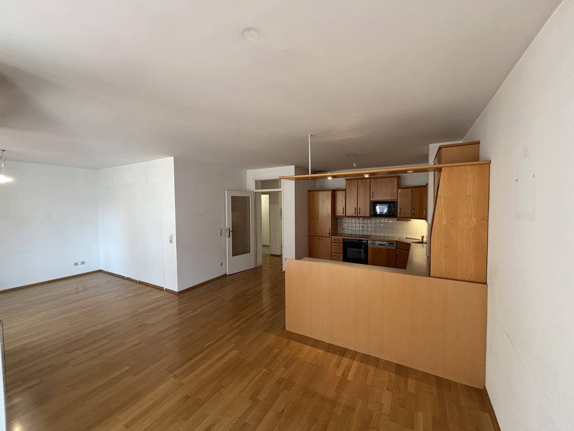 Heller offener Wohn- und Essbereich mit Holzboden und einer integrierten Küche mit Frühstückstheke.