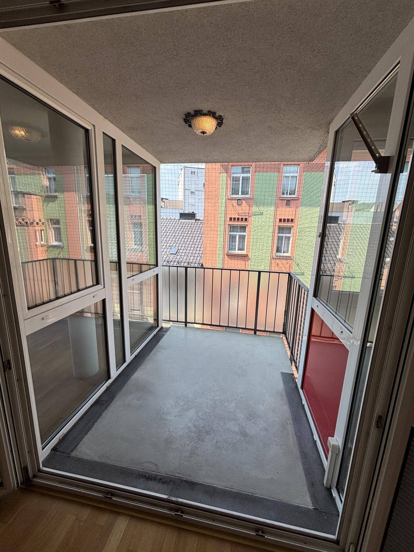 Verglaster Balkon mit Metallgeländer und Blick auf die umliegenden Gebäude, ideal für Entspannung.