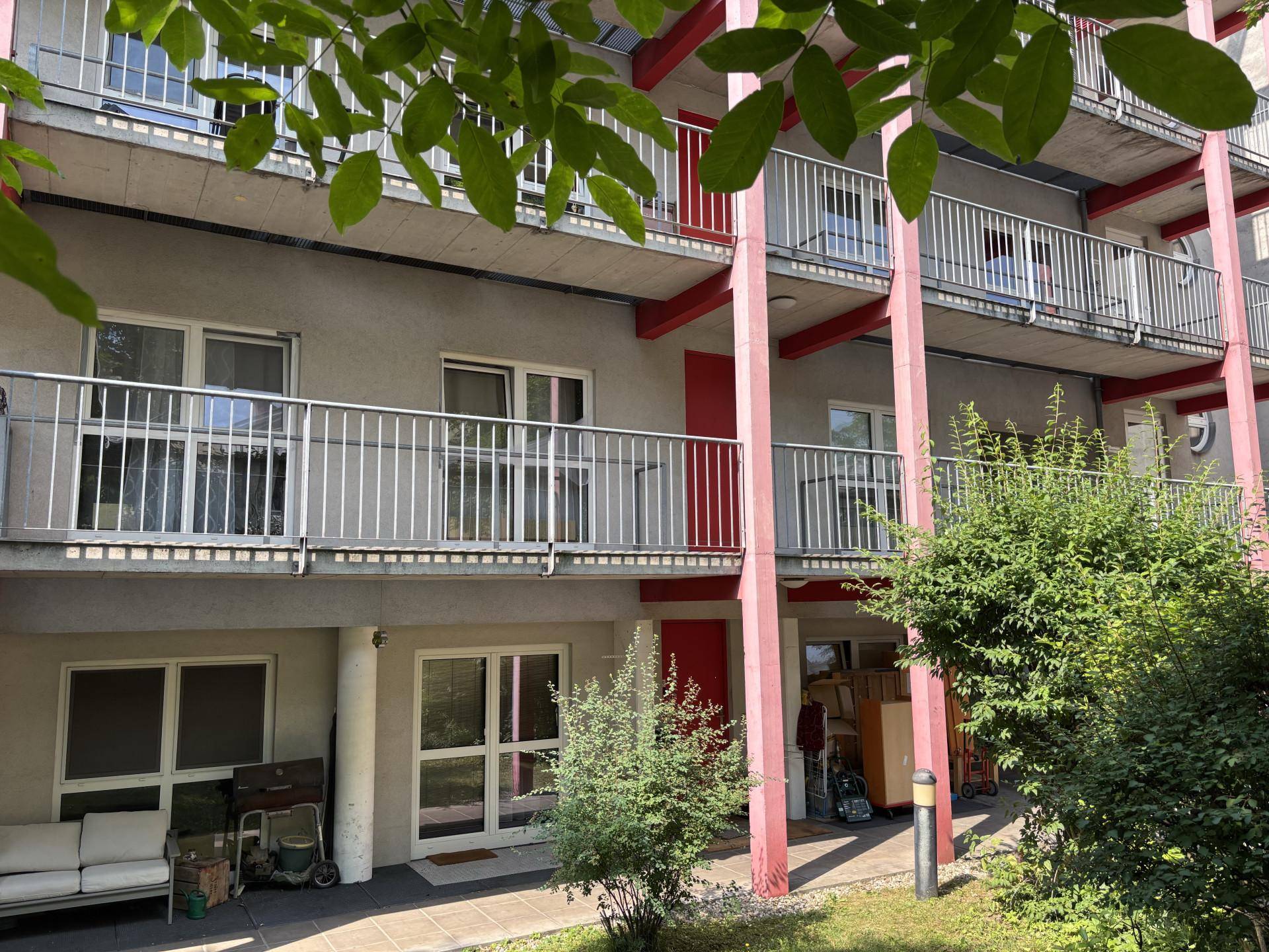Erdgeschossbereich mit kleinem Garten, Balkonen darüber und einer gemütlichen Sitzecke im Freien.