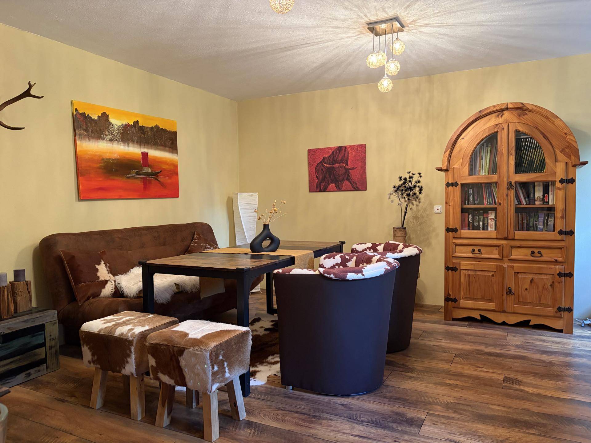 Rustikales Wohnzimmer mit Holzboden, braunem Sofa und einem großen Holzschrank im Landhausstil.
