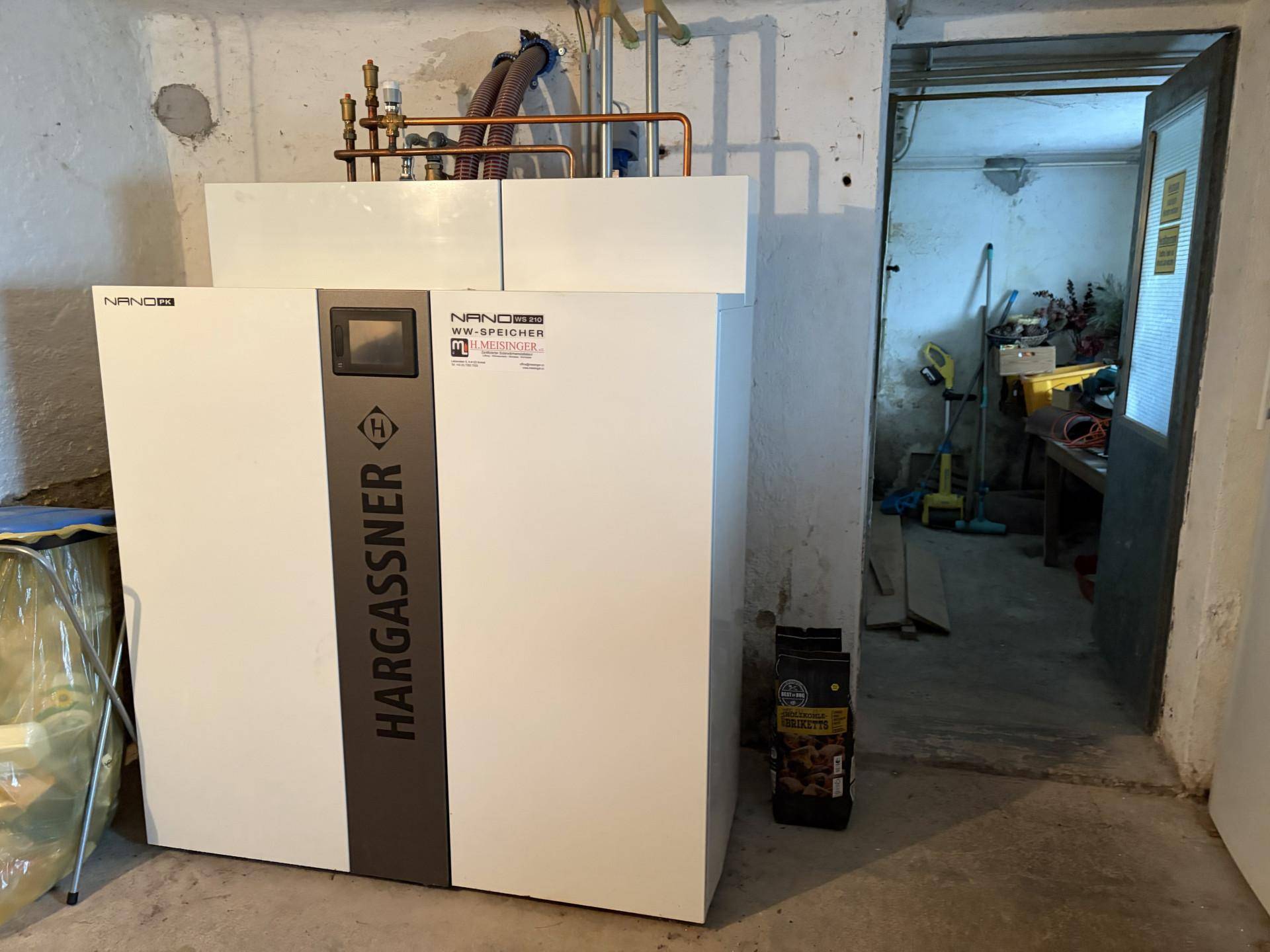 Heizungsraum im Keller mit moderner Hargassner Heizungsanlage und Lagerbereich.