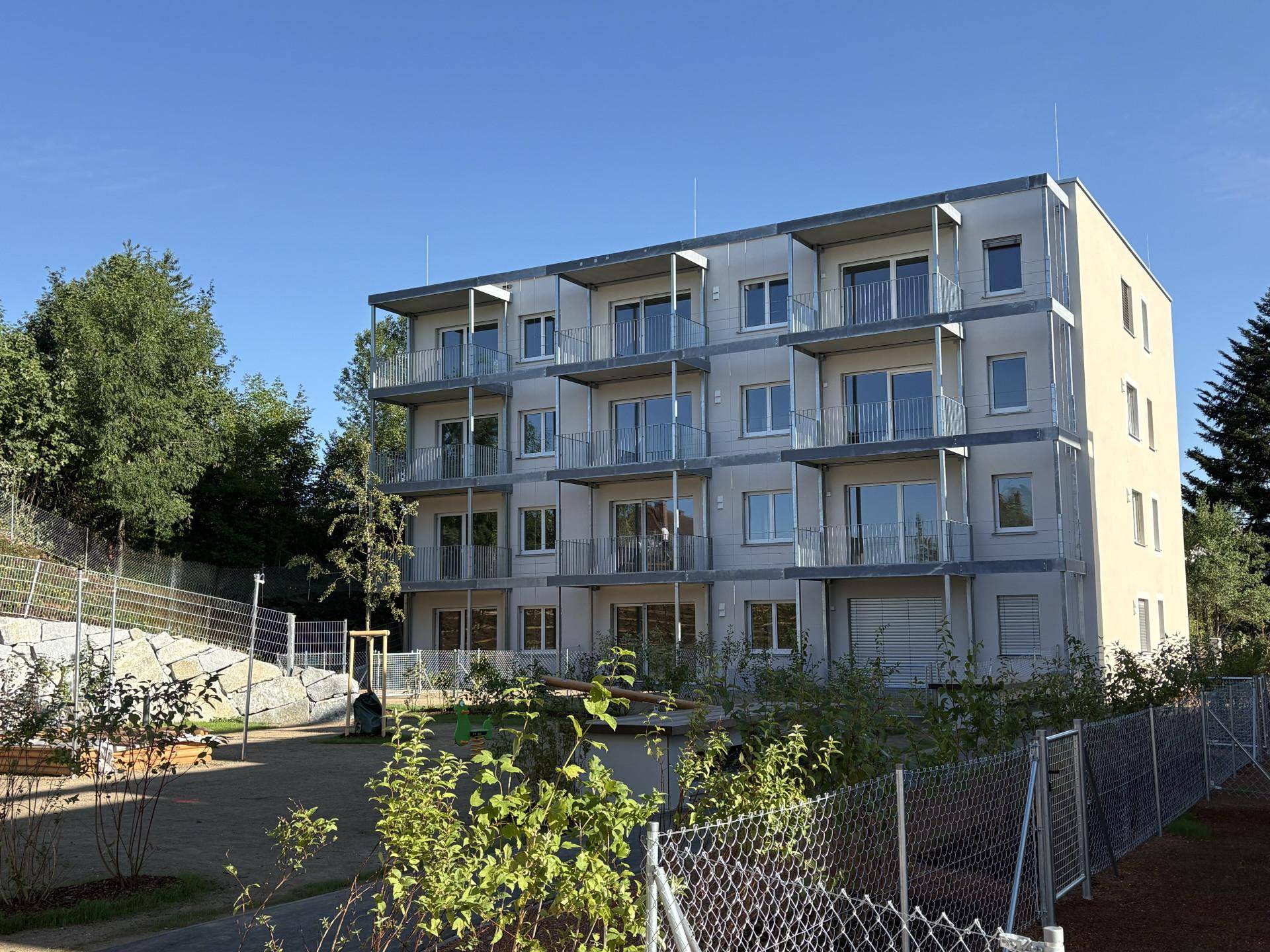Moderne Wohnanlage mit mehreren Balkonen und einer gepflegten Außenanlage im Sonnenlicht.